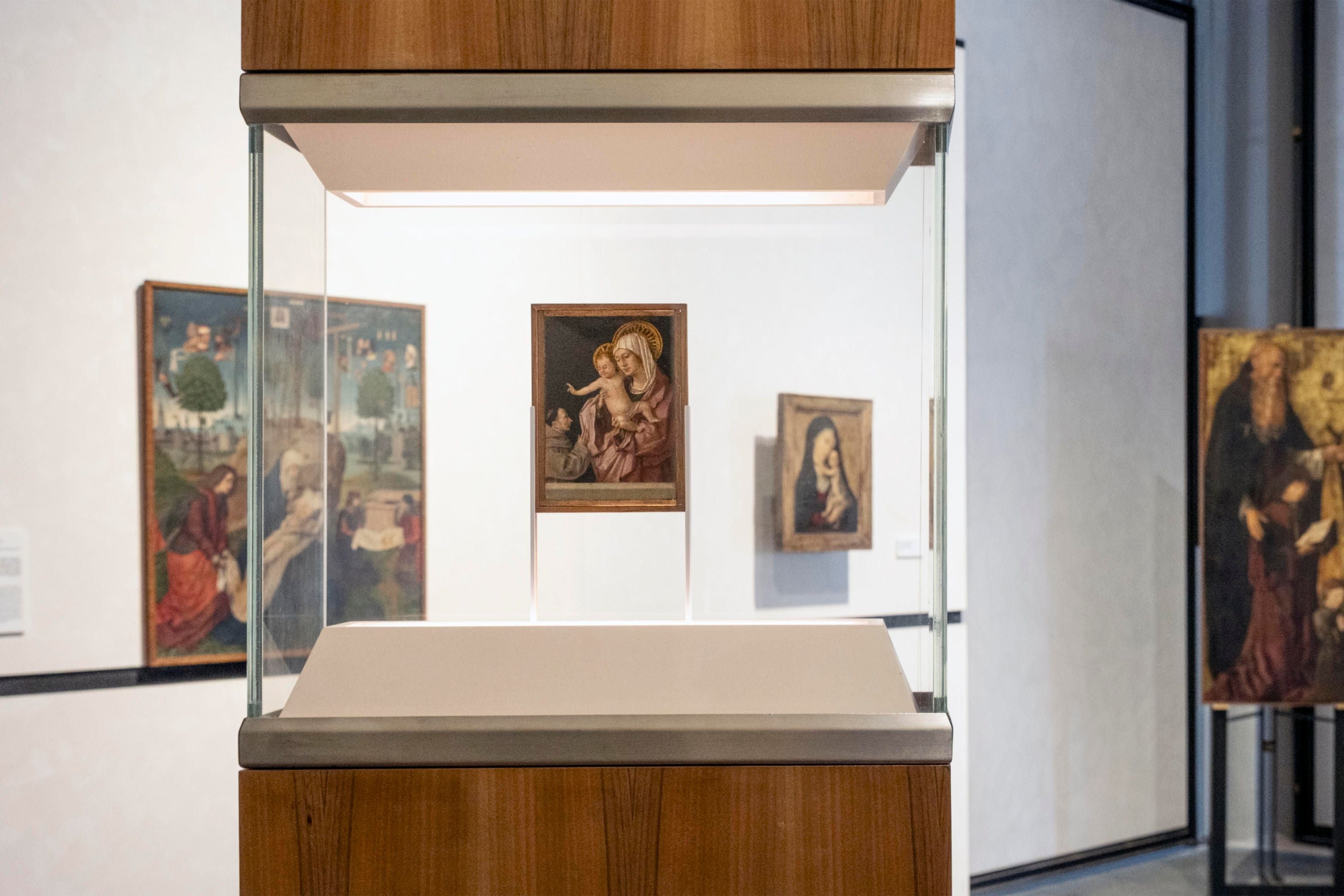 Ein kleines Gemälde von Madonna mit Kind in einer gläsernen Vitrine in einem Museumsausstellungsraum.