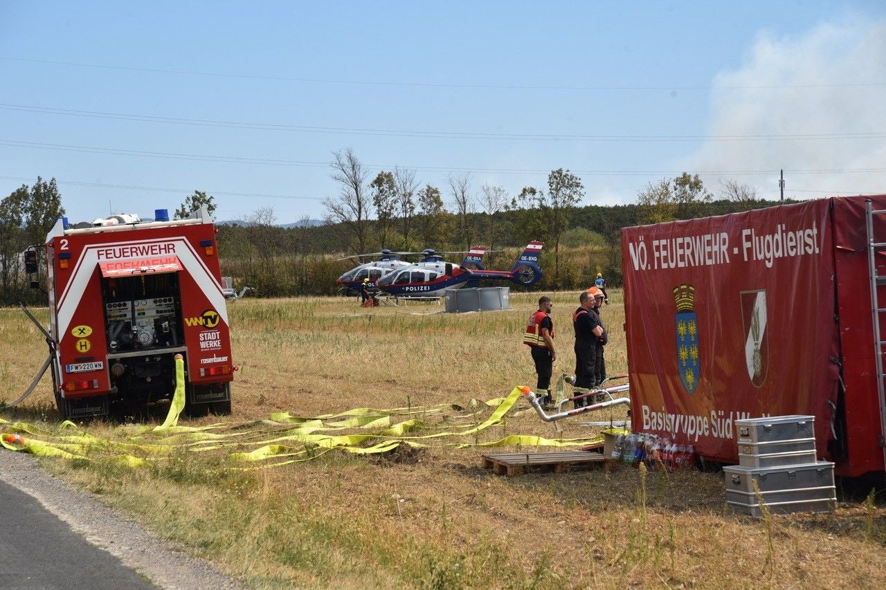 Feuerwehreinsatz mit Einsatzfahrzeug, Ausrüstung und zwei Polizeihubschraubern auf einem Feld.