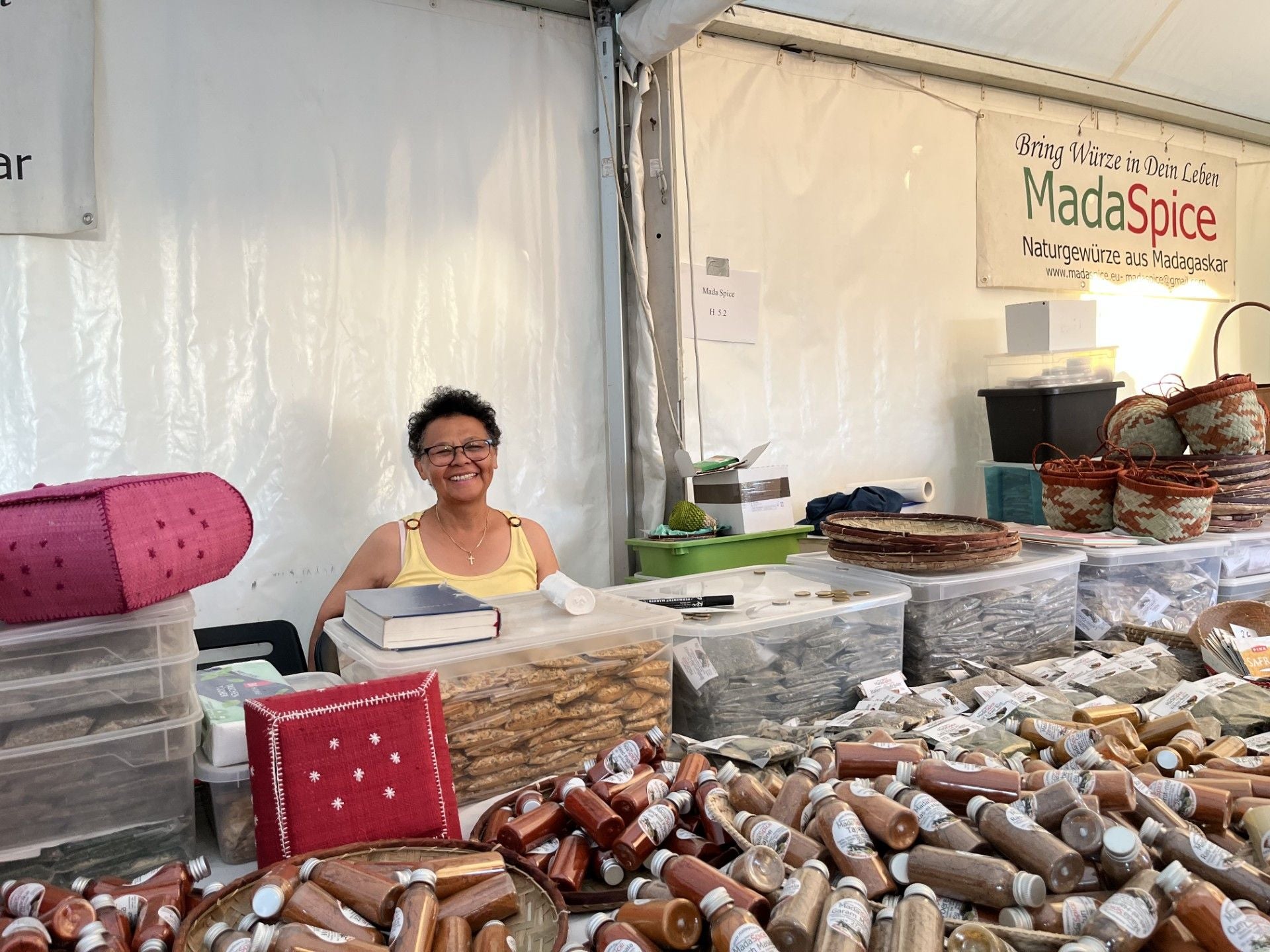 Frau an einem Verkaufsstand mit Gewürzen und geflochtenen Körben auf dem Afrika Tage Markt.