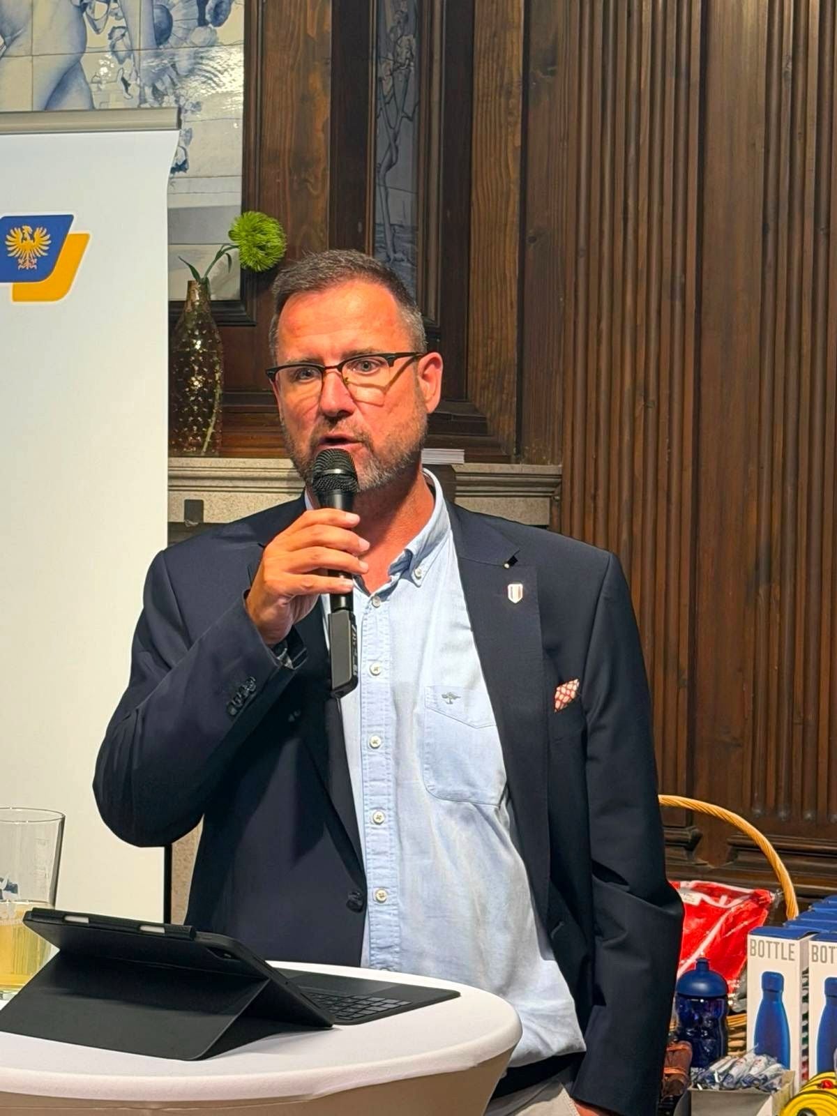 Ein Mann im Anzug spricht bei einer Veranstaltung in ein Mikrofon.