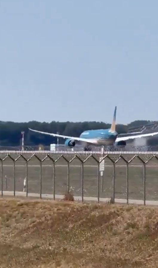 Ein Flugzeug landet auf einer Startbahn am Flughafen München bei klarem Himmel.
