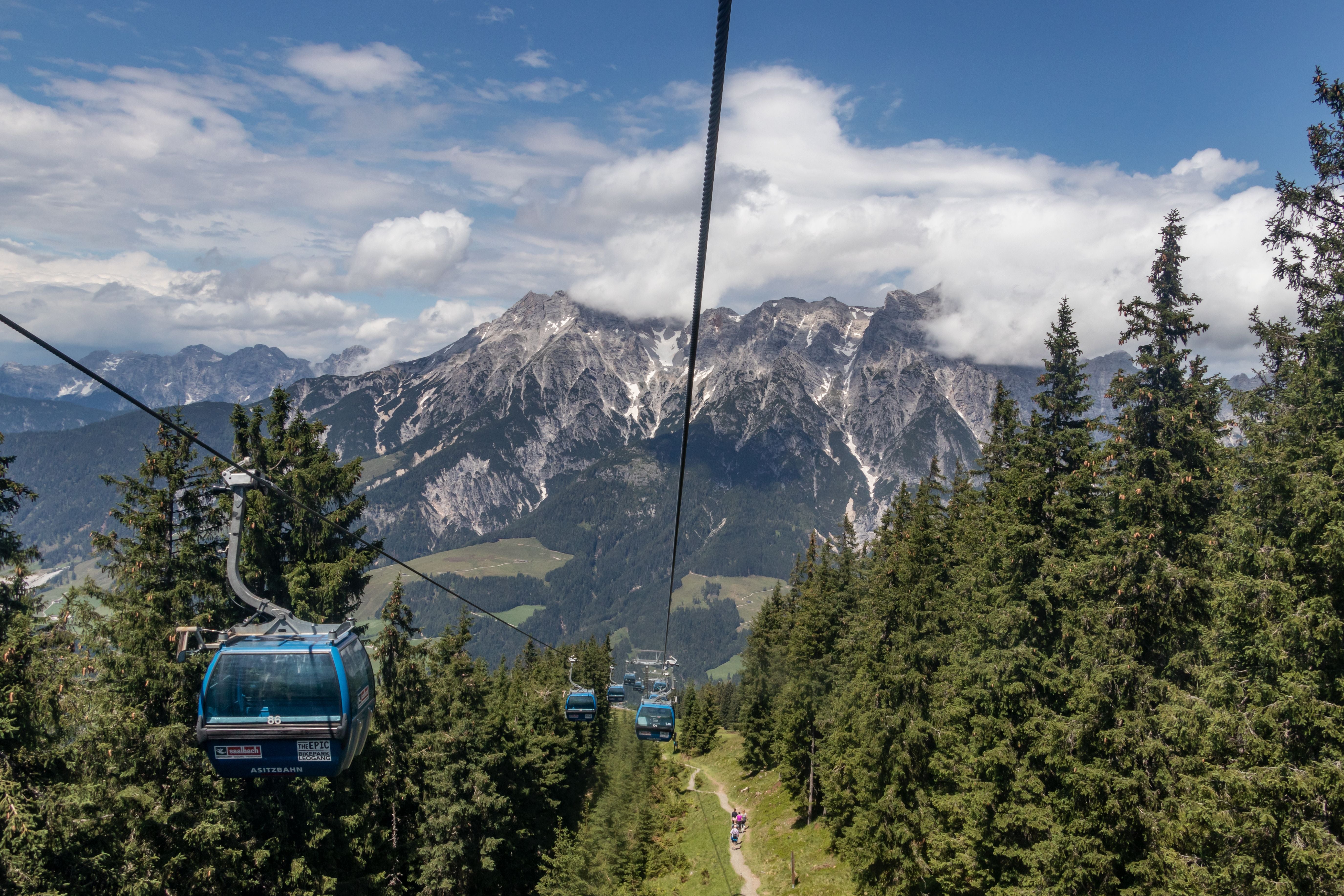 Blick auf die Asitzbahn-Gondeln in Leogang vor dem Bergmassiv Steinernes Meer im Sommer.