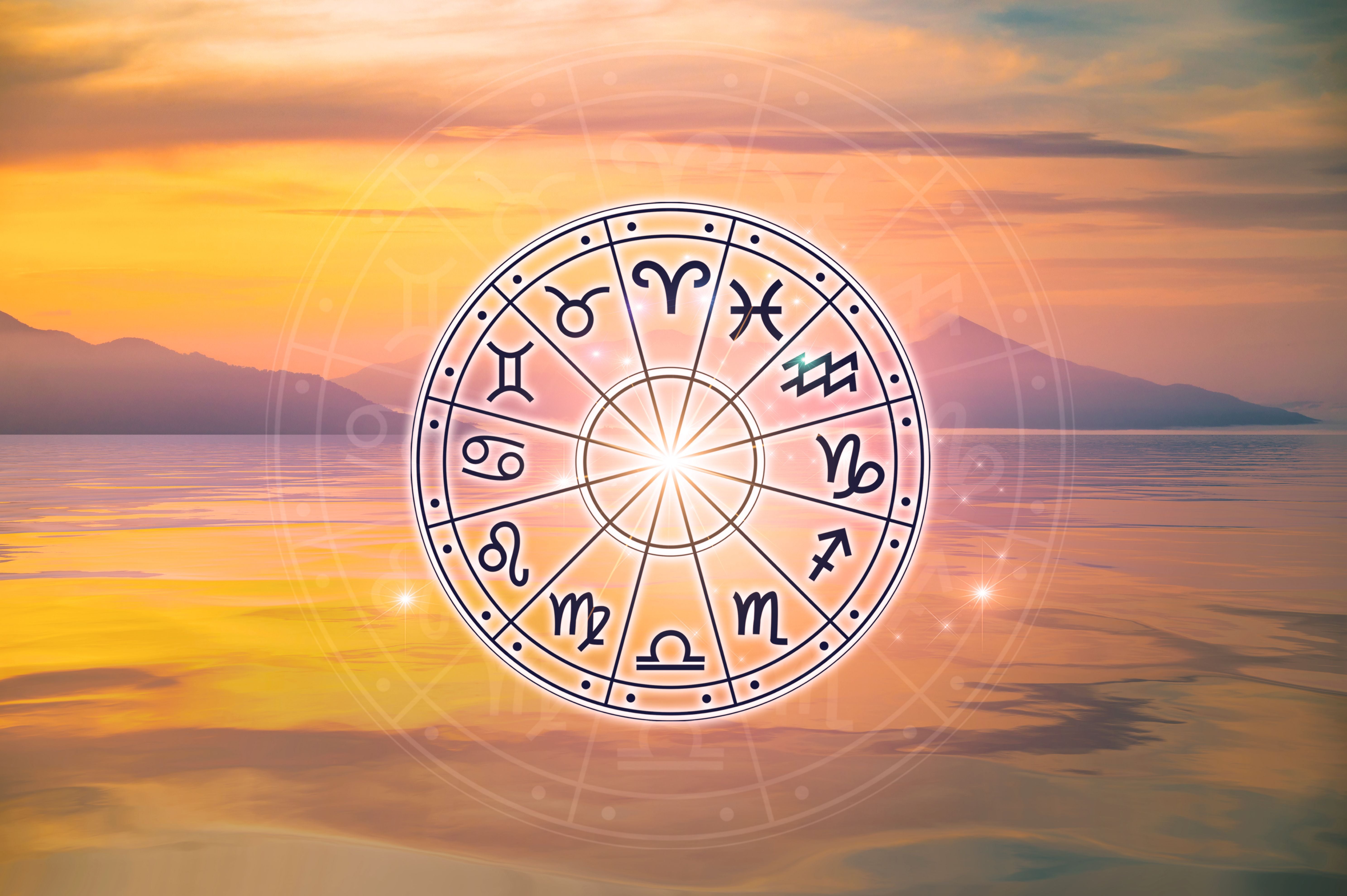 Horoskop-Kreis mit Tierkreiszeichen vor Sonnenuntergang über ruhigem Wasser und Bergen.