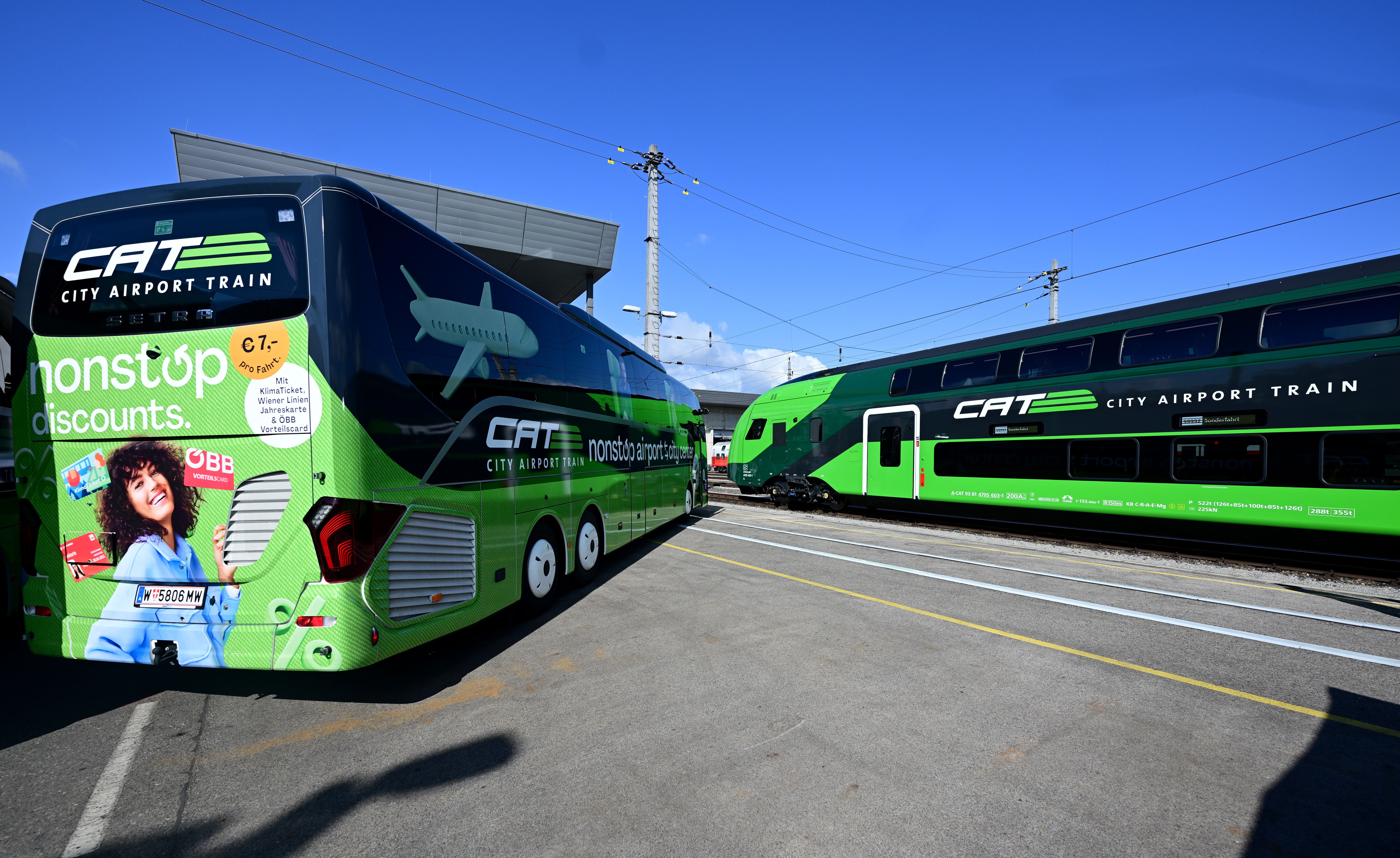 Ein CAT-Bus und ein City Airport Train stehen nebeneinander auf einem Gelände in Wien.