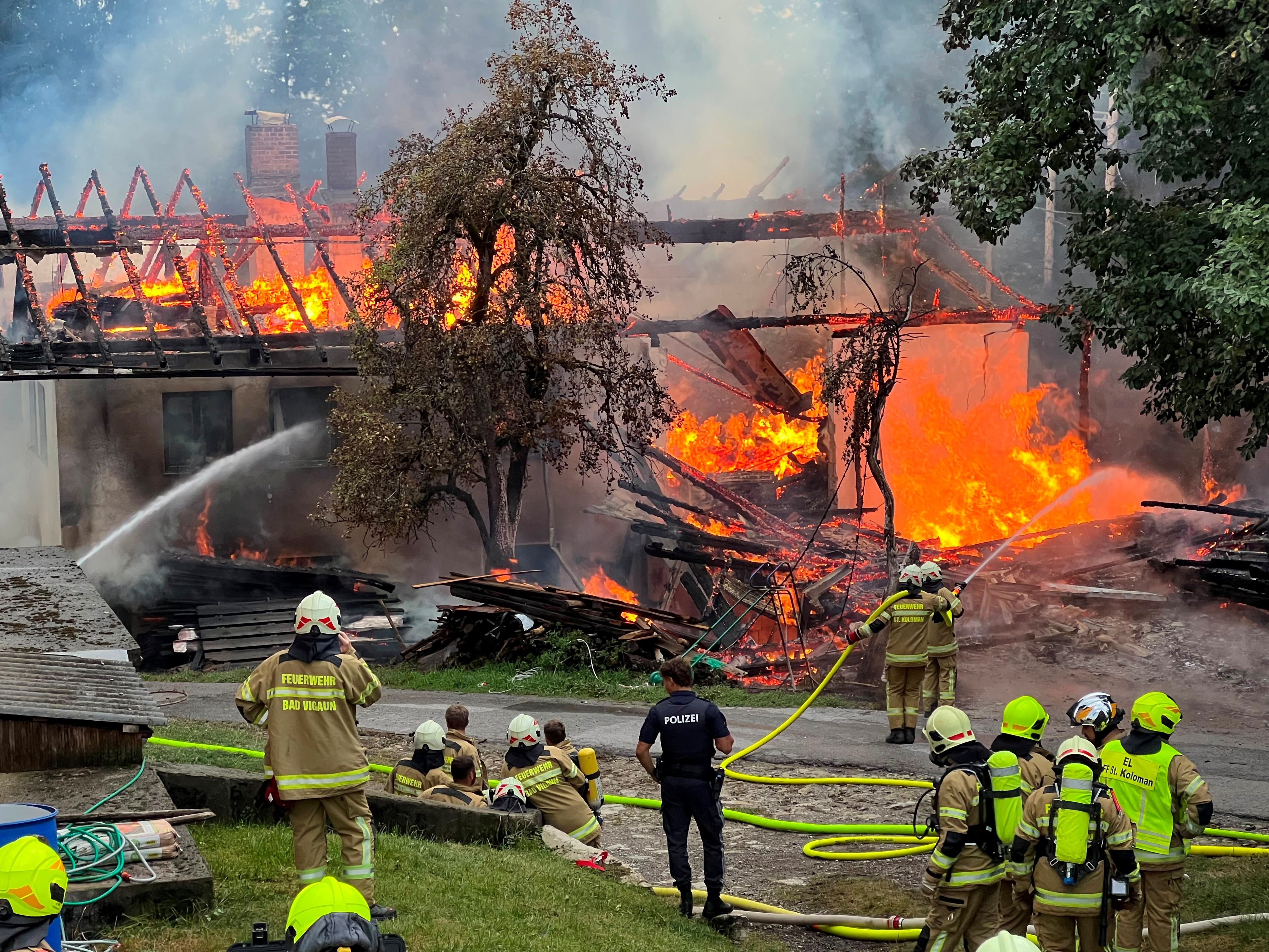 Feuerwehrleute bekämpfen einen Großbrand in einem brennenden Gebäude mit Wasserschläuchen.