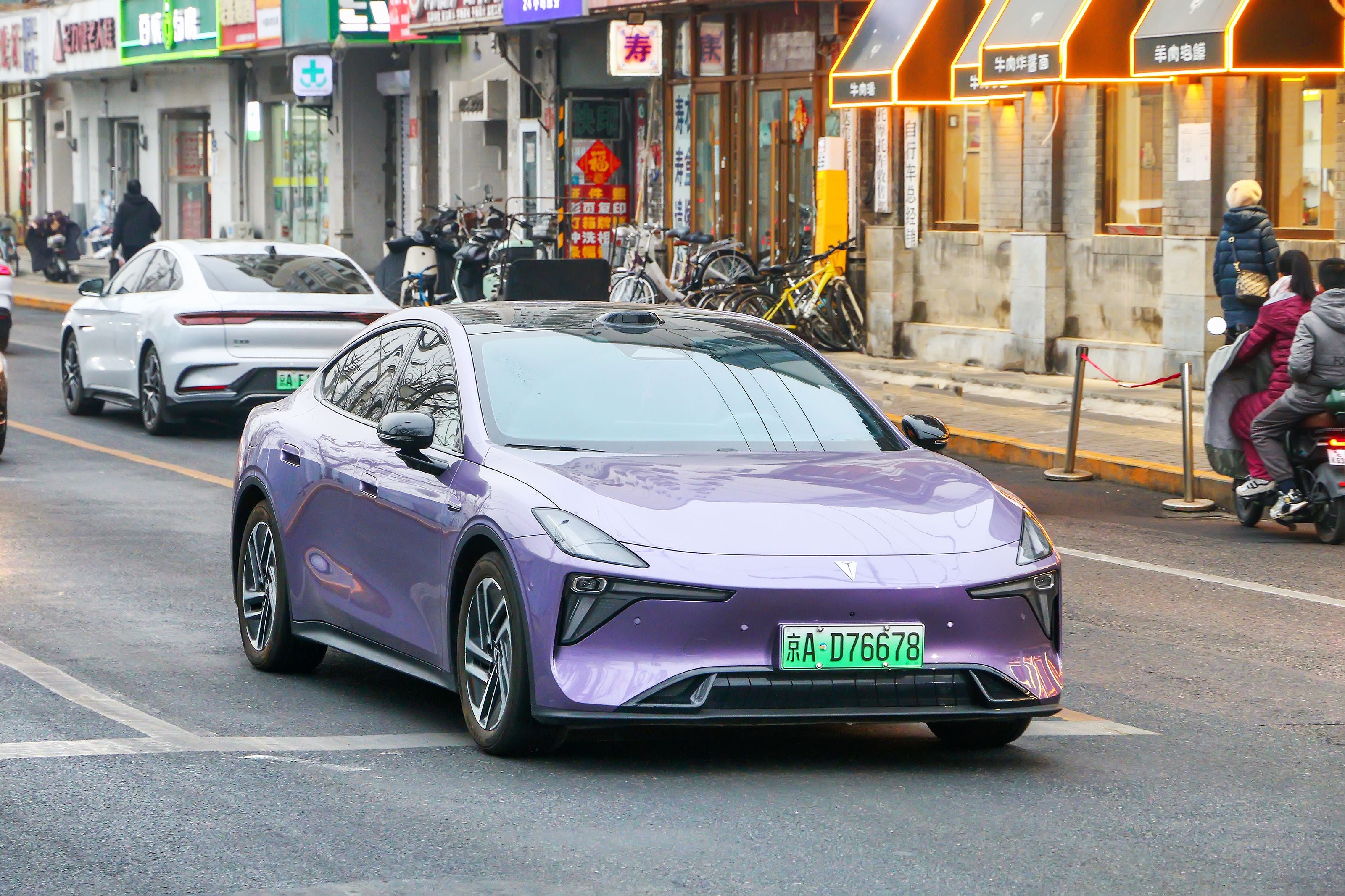 Lila Deepal L06 Limousine fährt auf einer Straße in Peking, im Hintergrund Geschäfte.