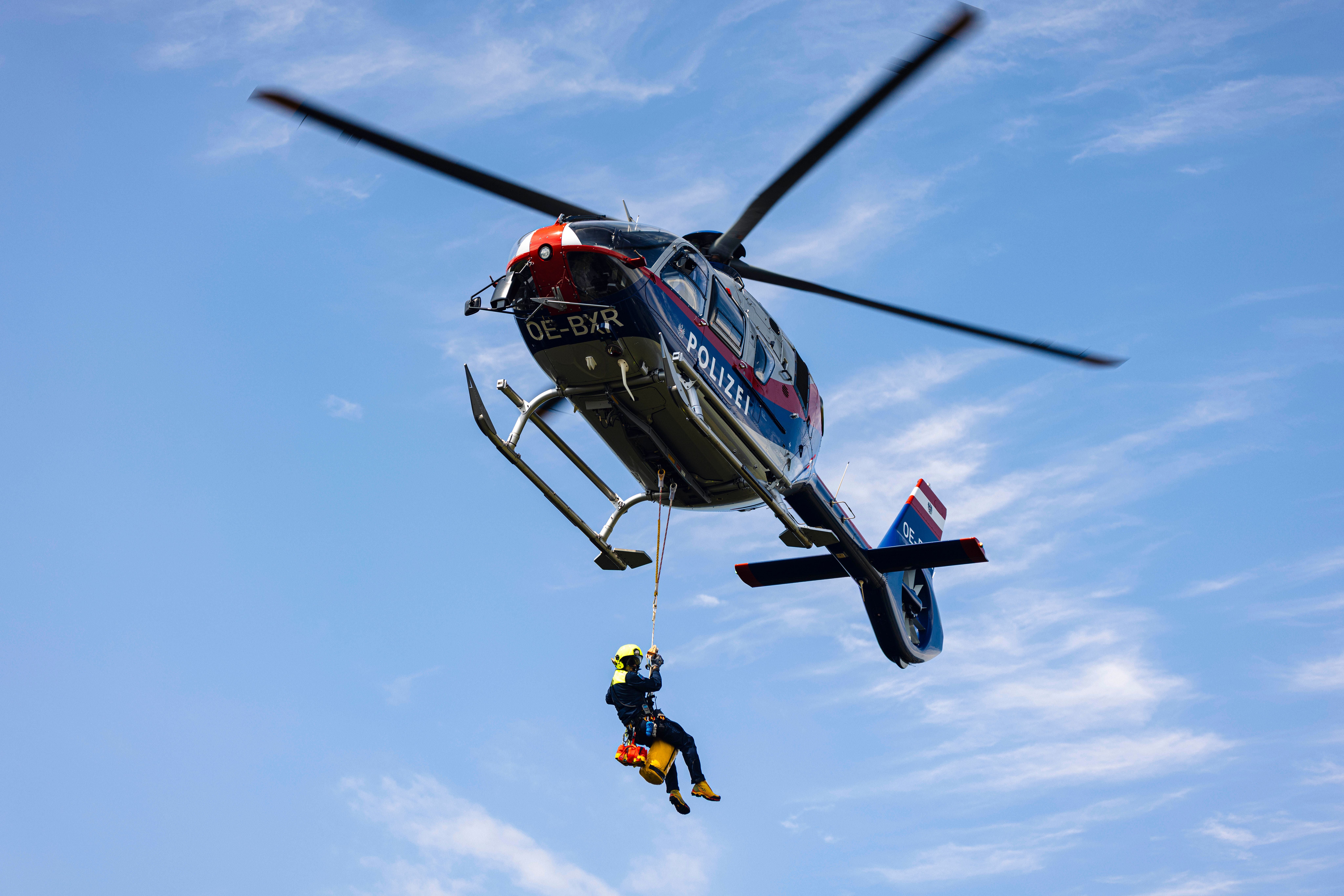 Polizei-Hubschrauber lässt eine Person mit Seilwinde am Seil herab.