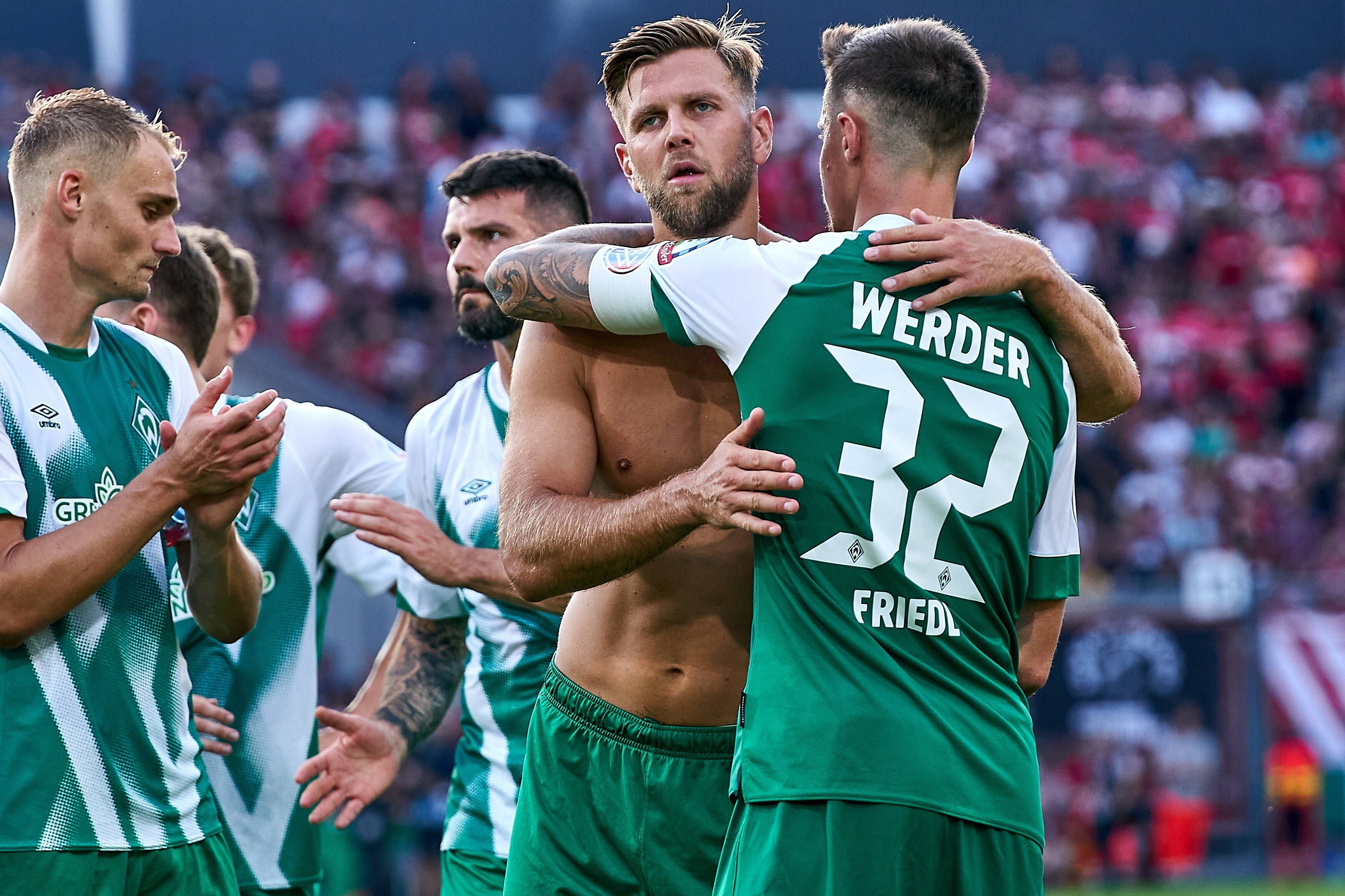 Mehrere Werder-Bremen-Spieler umarmen sich nach einem Fußballspiel im Stadion.