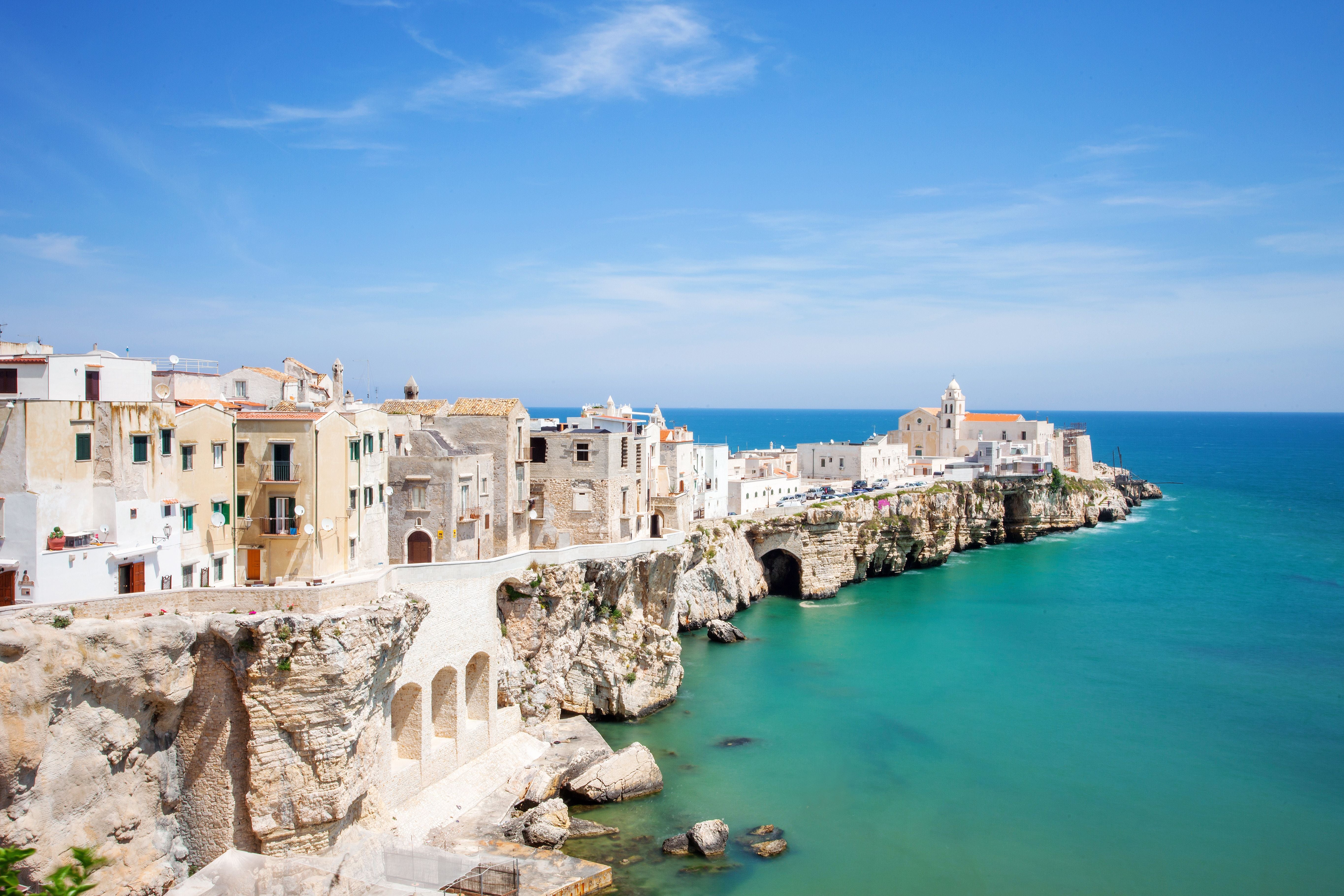 Blick auf die Küstenstadt Vieste mit Häusern auf Felsen und türkisblauem Meer.