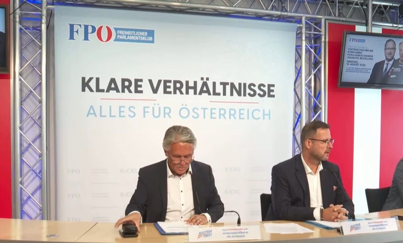 Zwei Männer sitzen bei einer FPÖ-Pressekonferenz vor einem Banner mit Slogan.