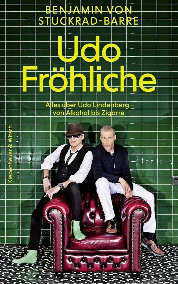 Buchcover mit zwei Männern auf rotem Ledersessel vor grüner Kachelwand, Titel „Udo Fröhliche“.
