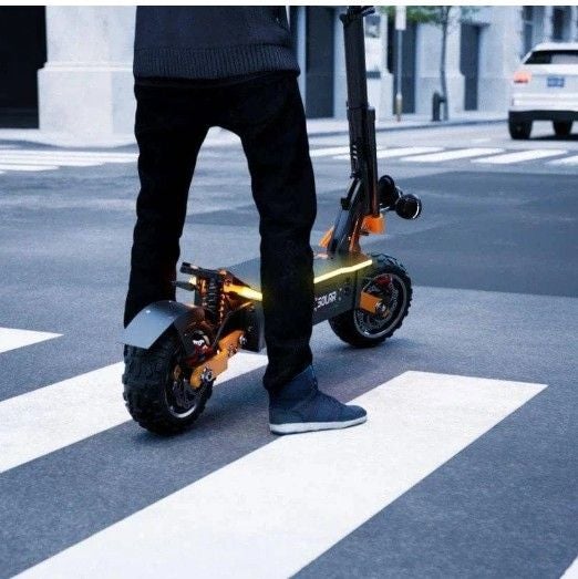 Person mit einem E-Scooter überquert einen Zebrastreifen in einer Stadt.