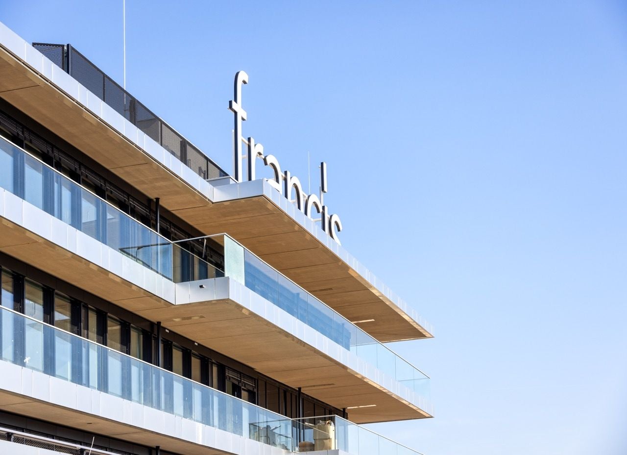Modernes Gebäude mit Schriftzug "Francis" auf dem Dach vor blauem Himmel.