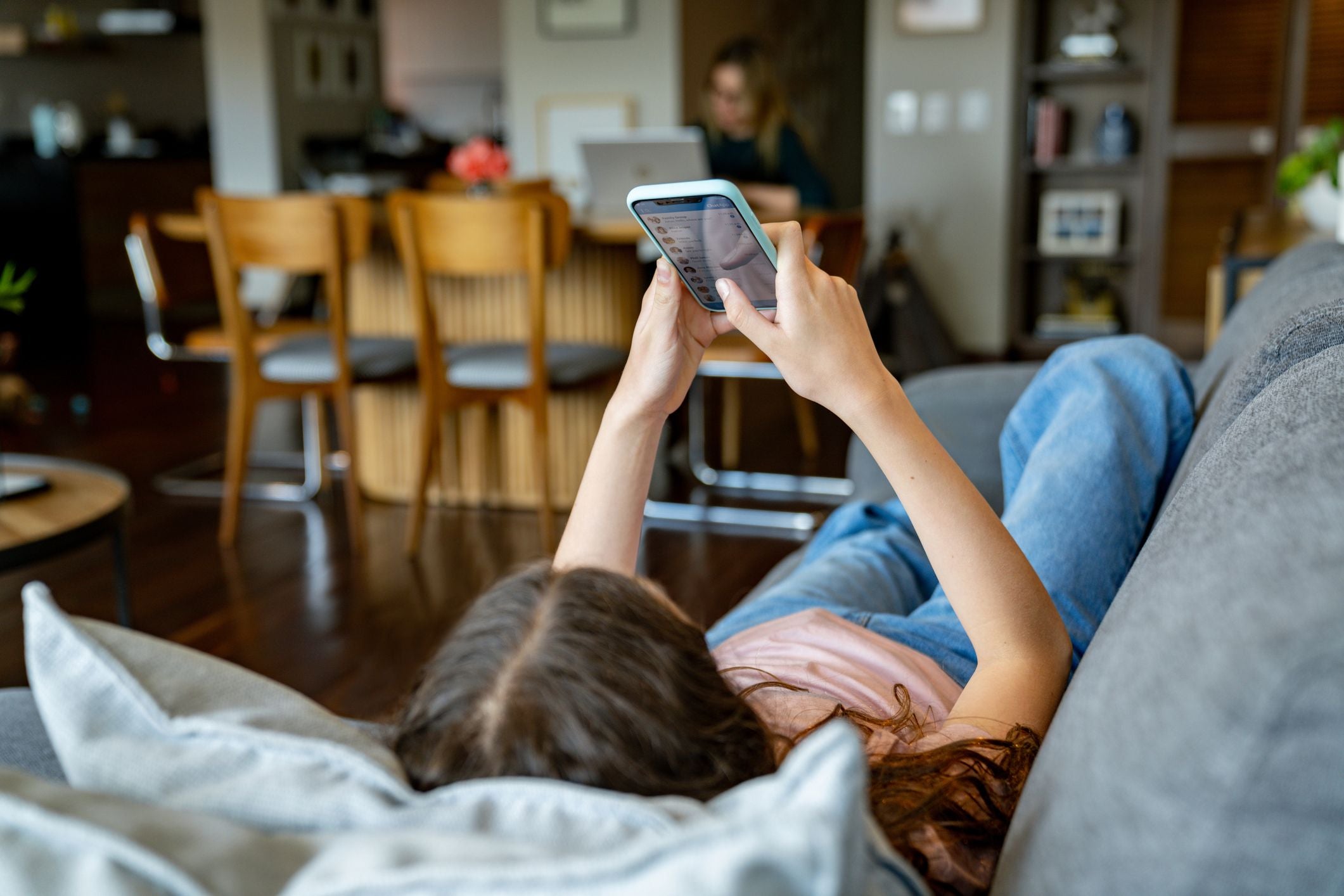 Teenager liegt auf dem Sofa und schaut auf ihrem Handy soziale Medien an.