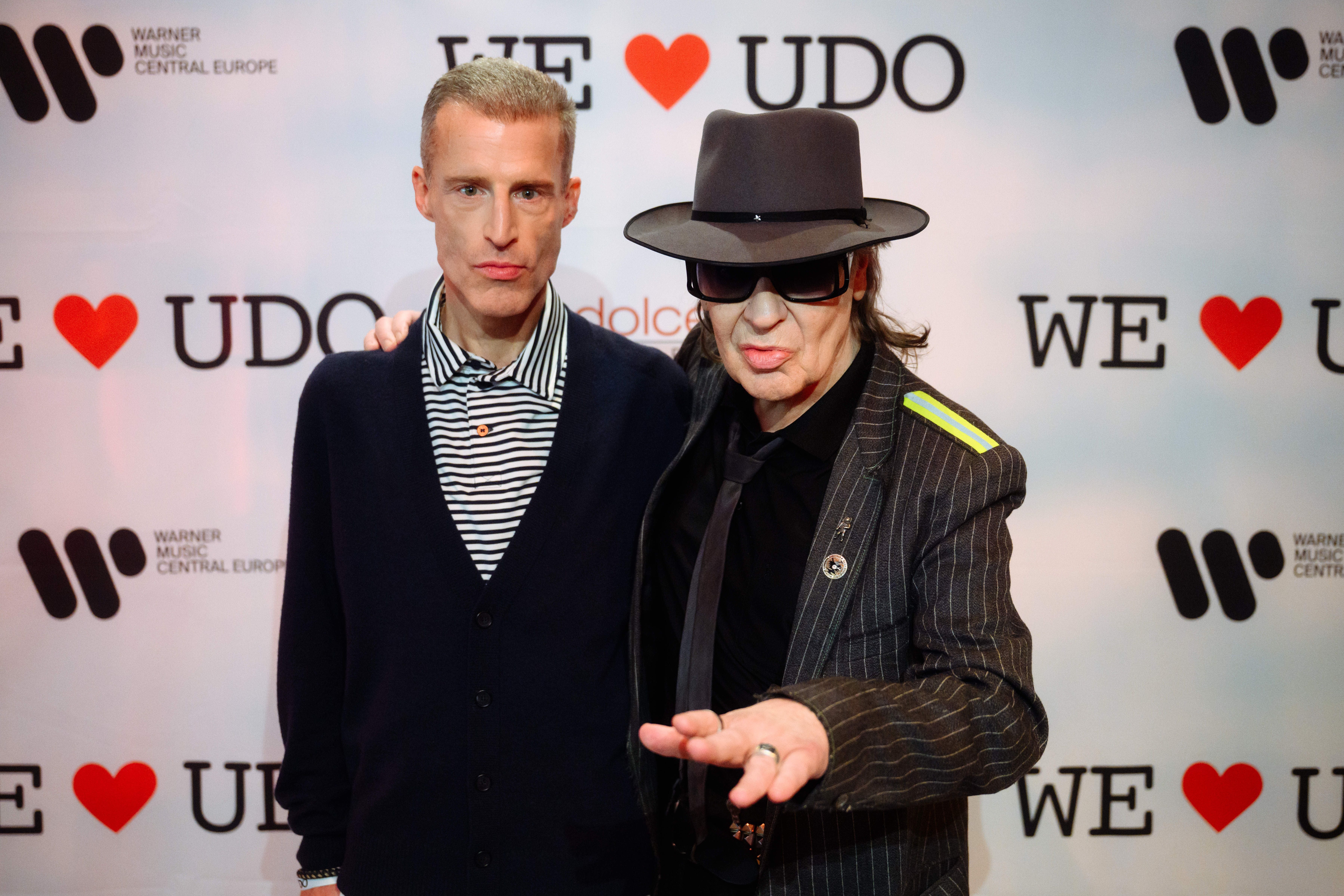 Zwei Männer posieren vor einer „We love Udo“-Fotowand bei einer Veranstaltung in Hamburg.