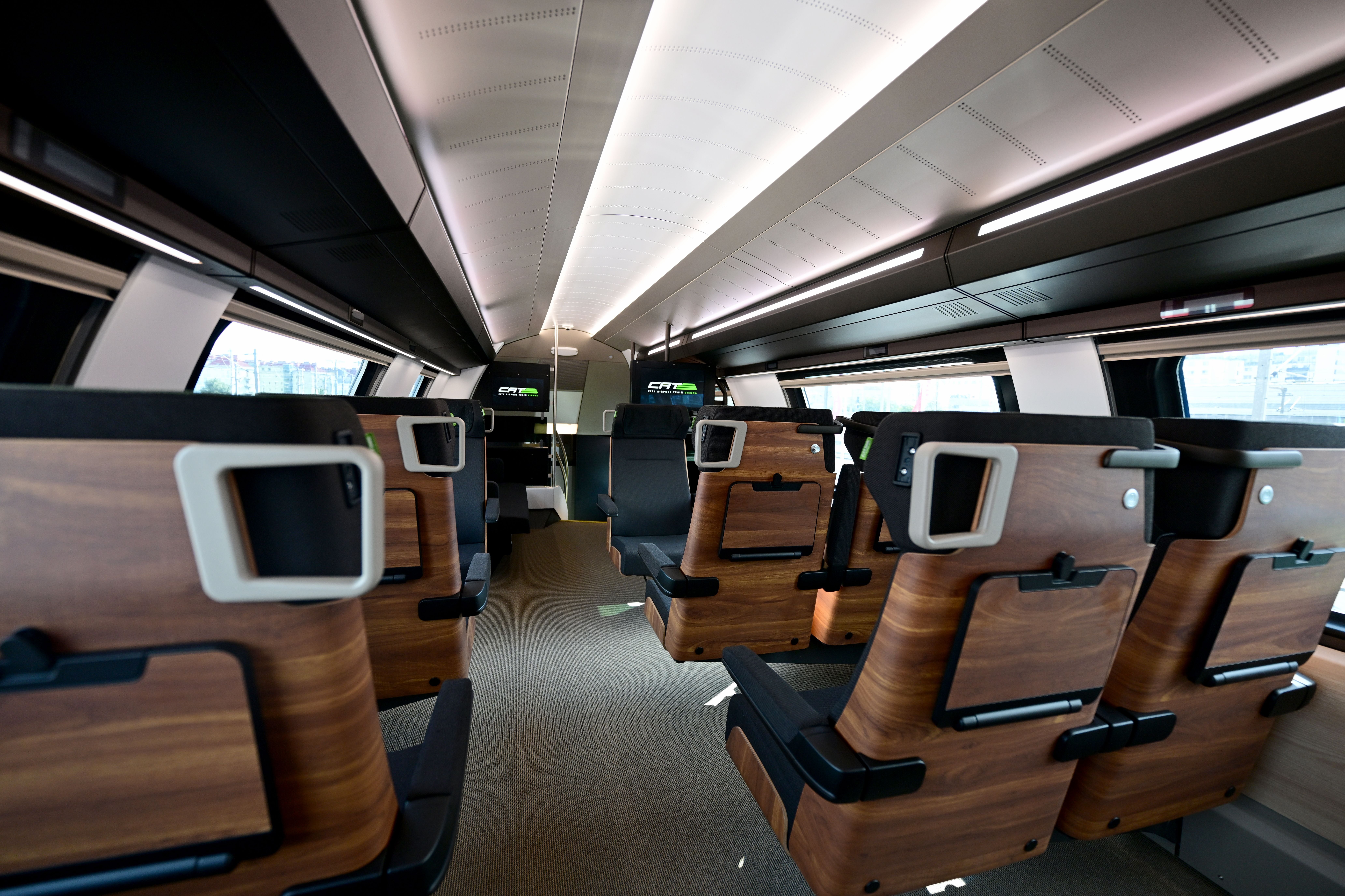 Modernes, geräumiges Interieur eines City Airport Train mit Holzsitzen und großen Fenstern.