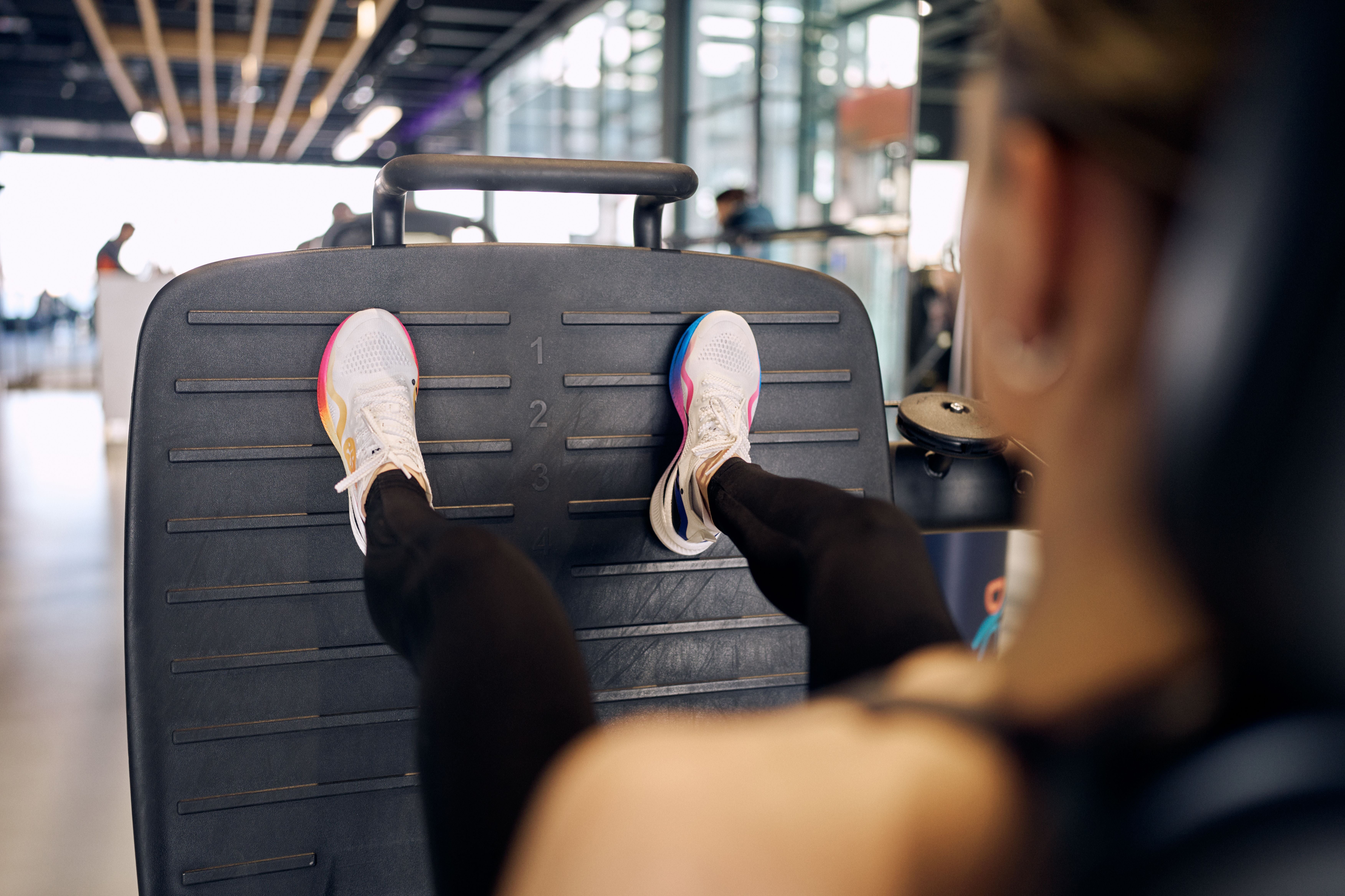 Frau positioniert ihre Füße korrekt auf der Beinpresse im Fitnessstudio.
