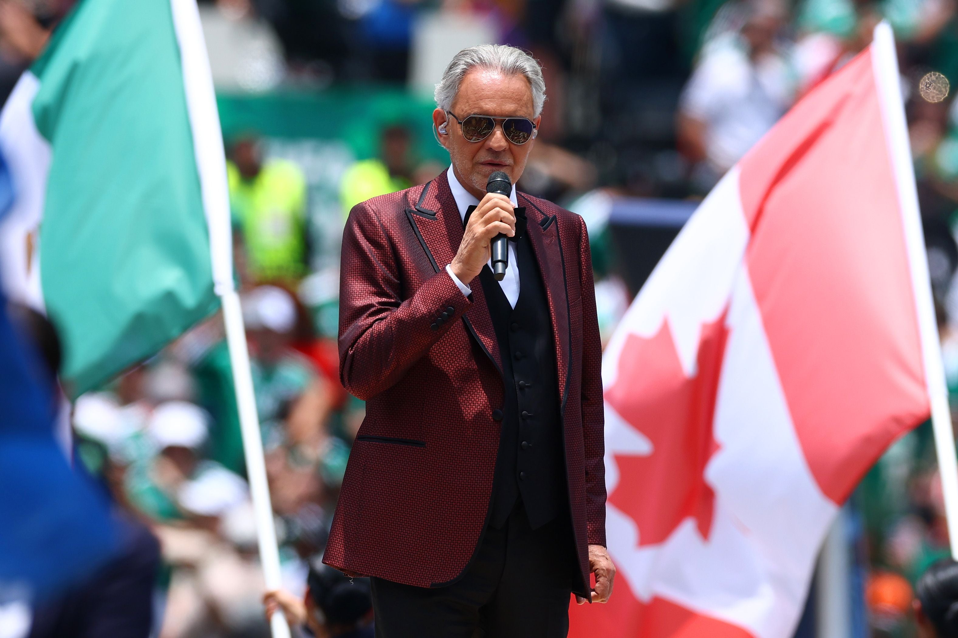Ein Mann im Anzug singt mit Mikrofon, im Hintergrund eine kanadische Flagge.
