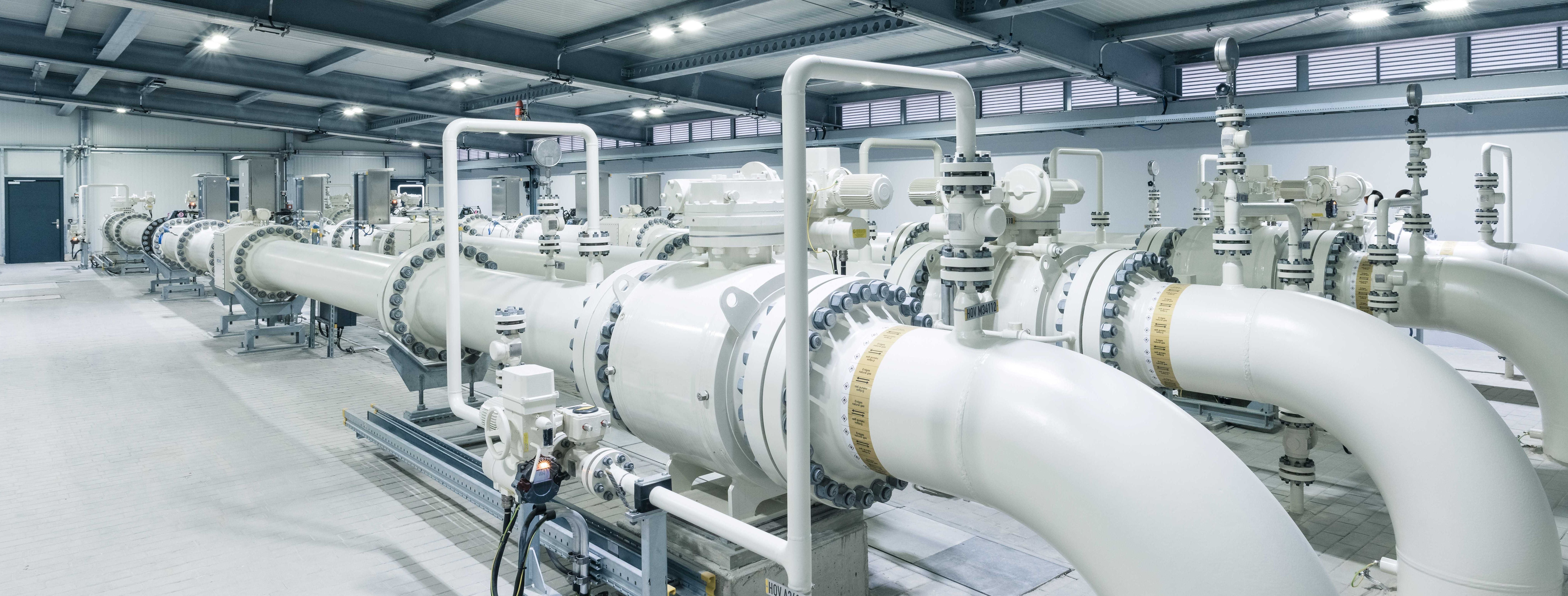 Große weiße Gasrohre und Ventile in einer modernen Industrieanlage für den Gastransport.