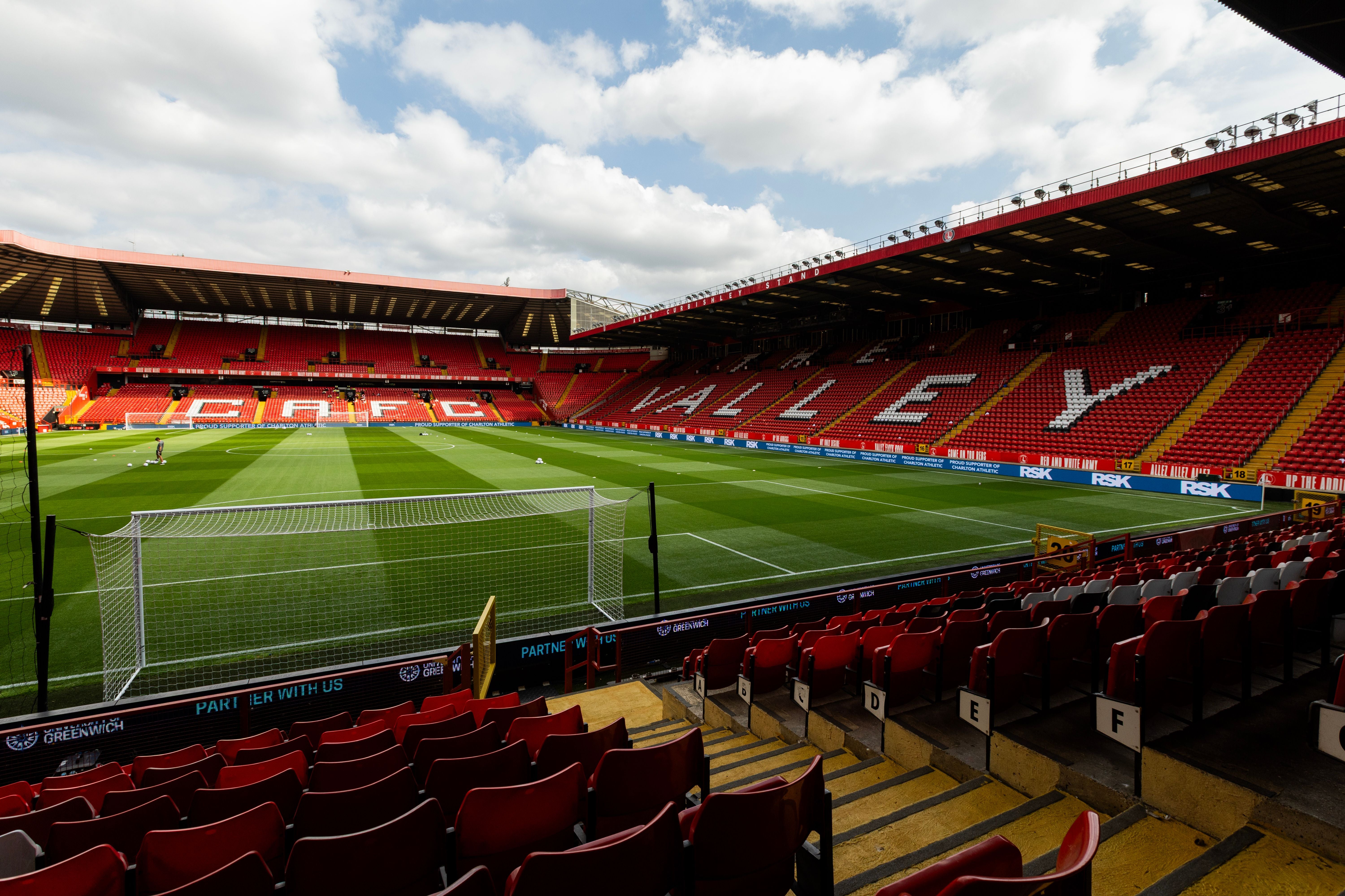 Leeres Fußballstadion „The Valley“ mit grünem Rasen und roten Sitzplätzen in London.