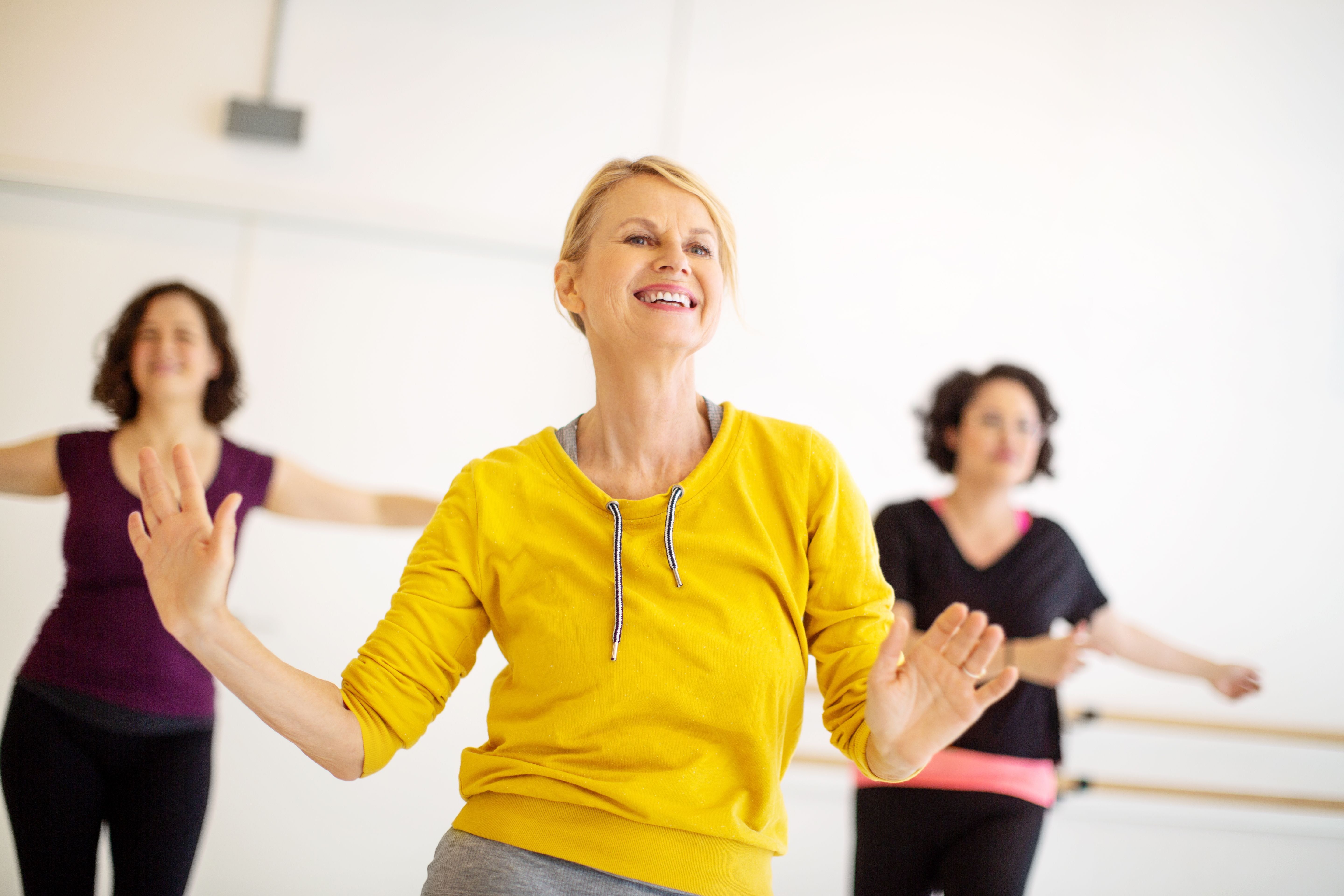 Mehrere Frauen tanzen gemeinsam fröhlich in einem Fitnessstudio.