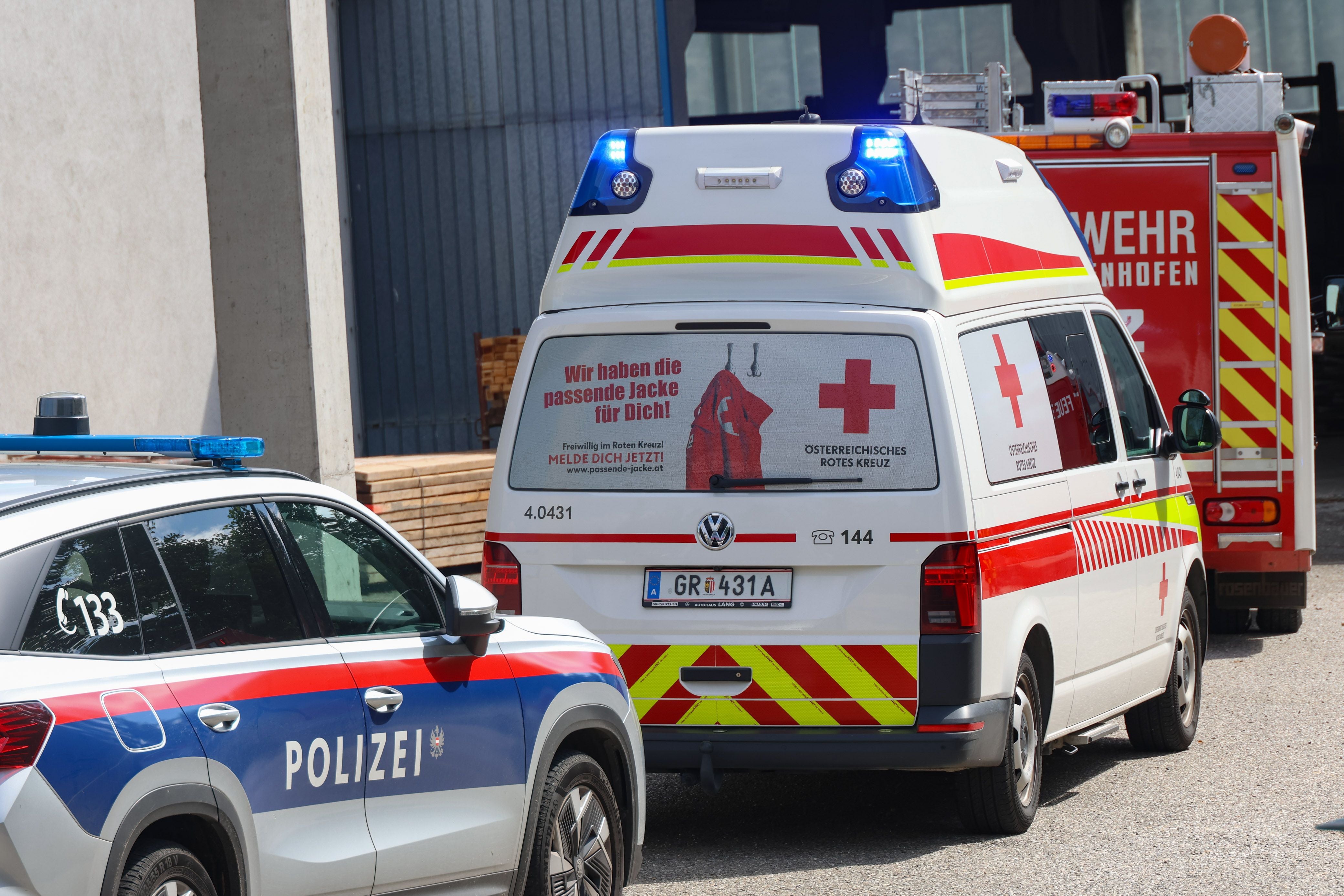 Polizei-, Rettungs- und Feuerwehrfahrzeuge stehen nebeneinander vor einem Gebäude.