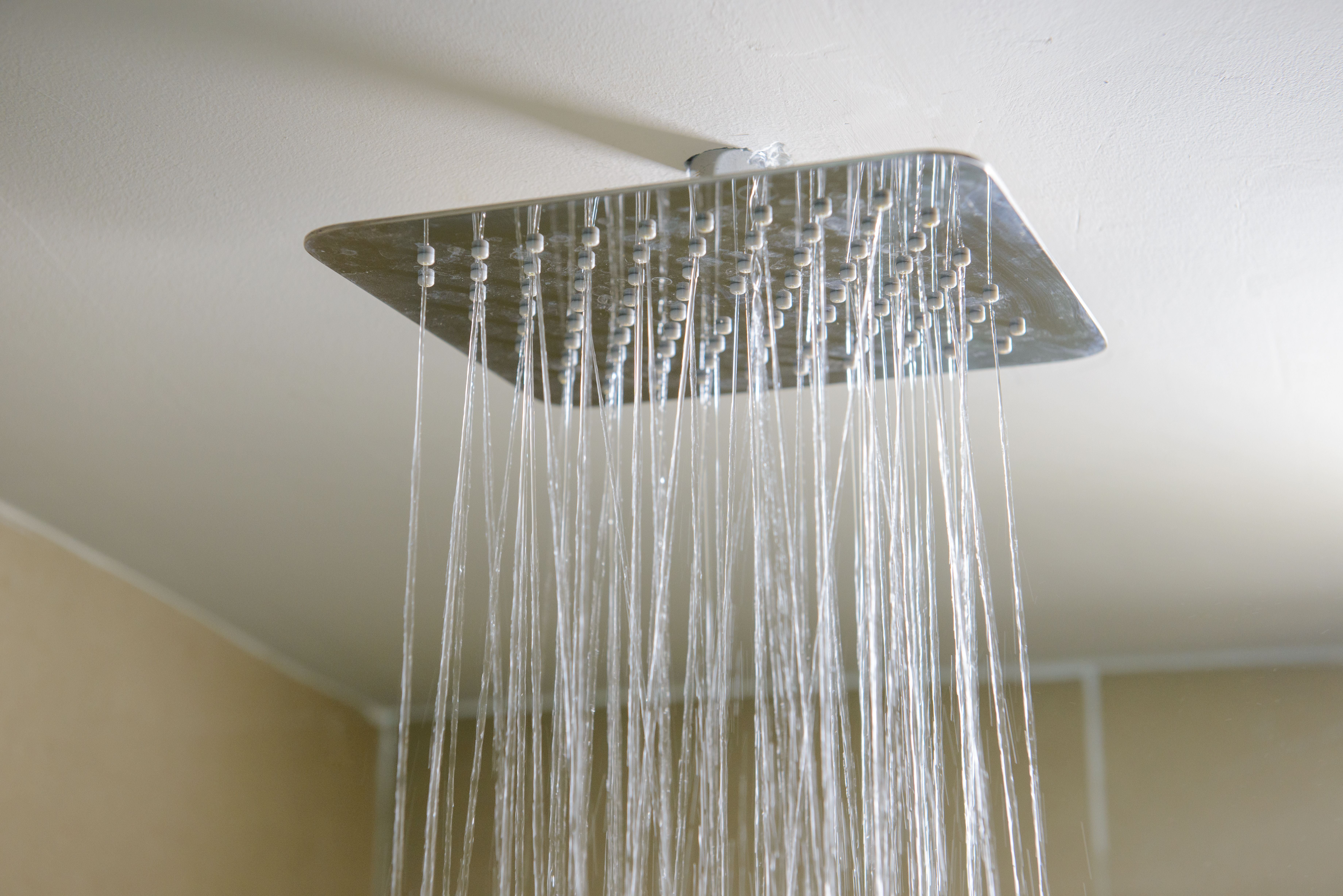 Quadratische Duschbrause mit fließendem Wasser von der Decke.