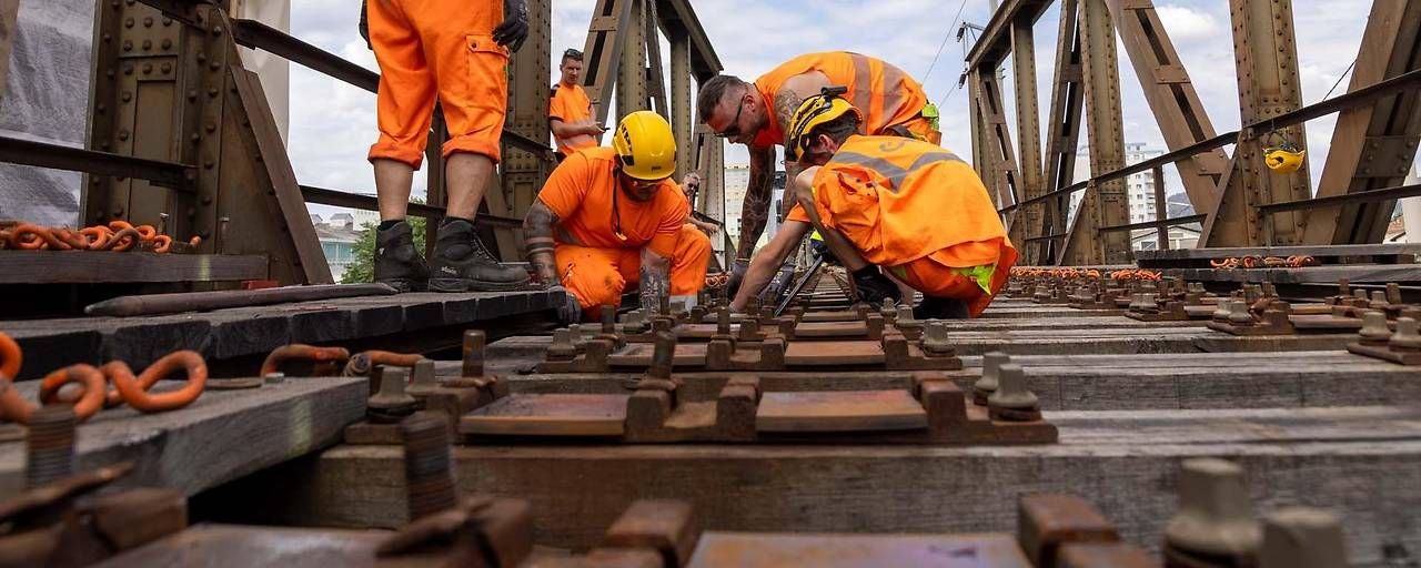 Bauarbeiter reparieren Gleise auf einer Eisenbahnbrücke.