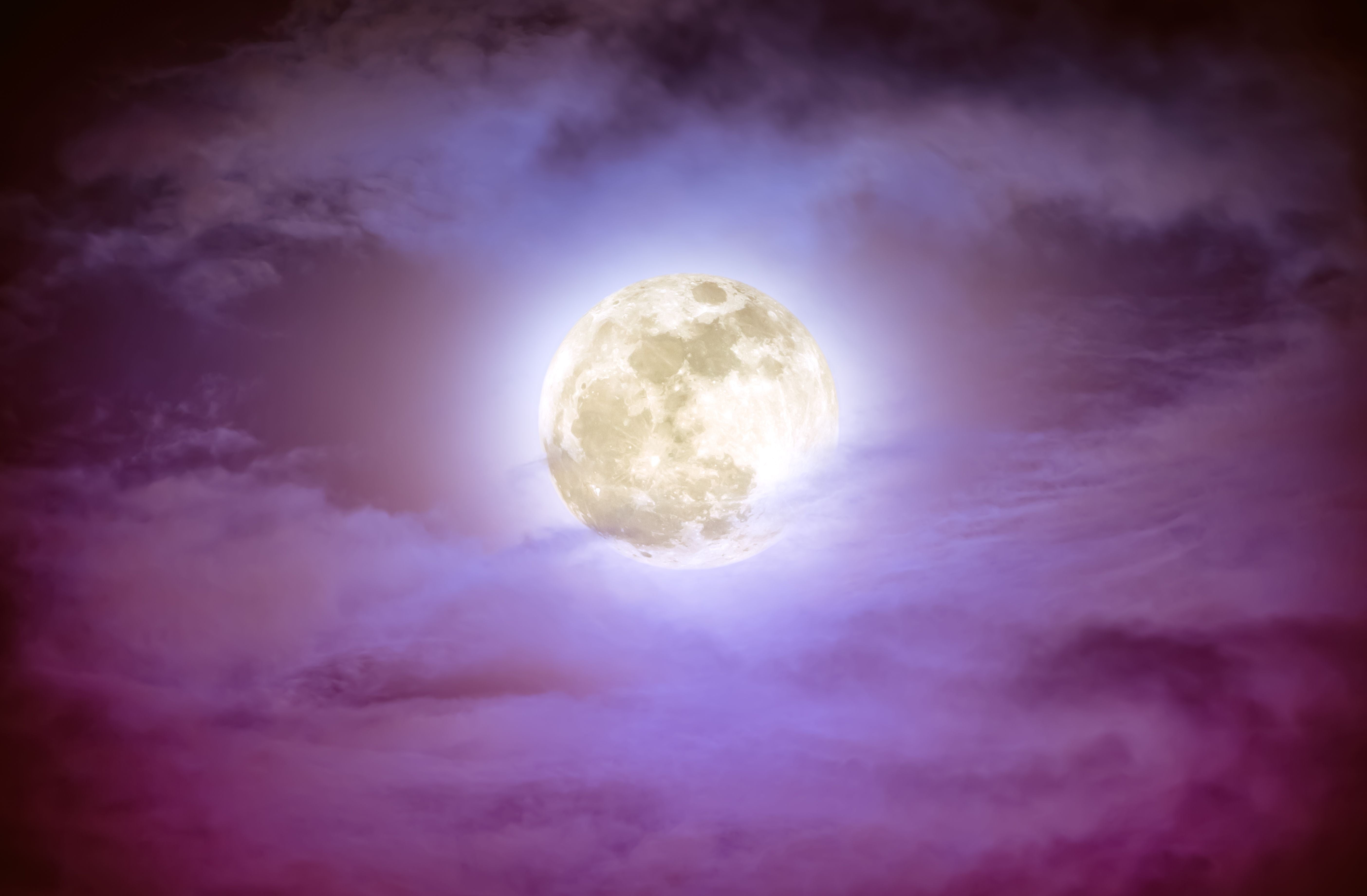 Vollmond leuchtet am Nachthimmel, umgeben von violetten und blauen Wolken.