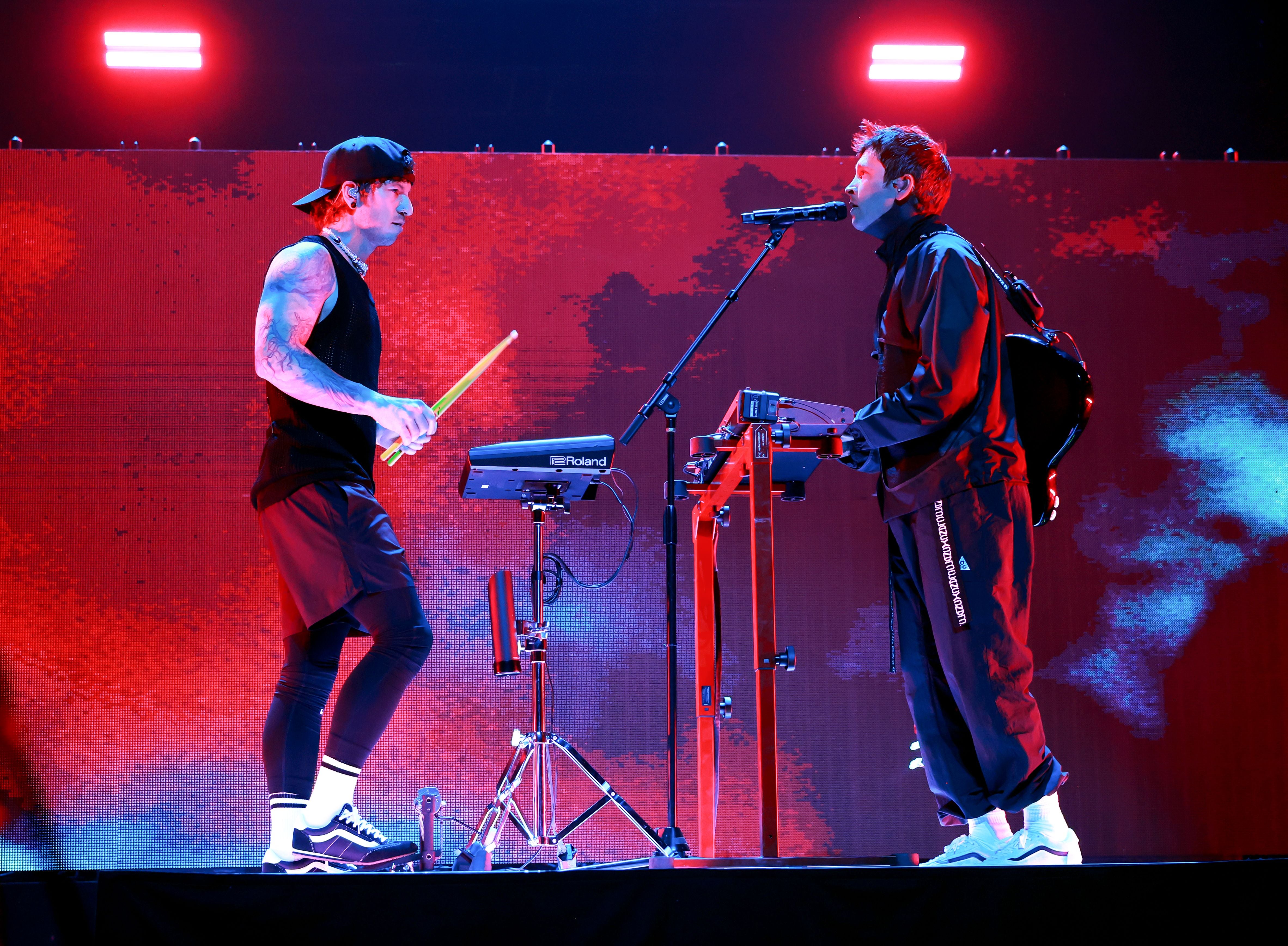 Zwei Musiker performen mit Keyboard und Schlagzeug auf einer rot beleuchteten Bühne.