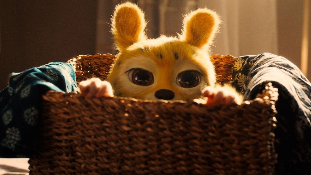 Plüschiges Marsupilami mit großen Augen schaut aus einem geflochtenen Korb hervor.
