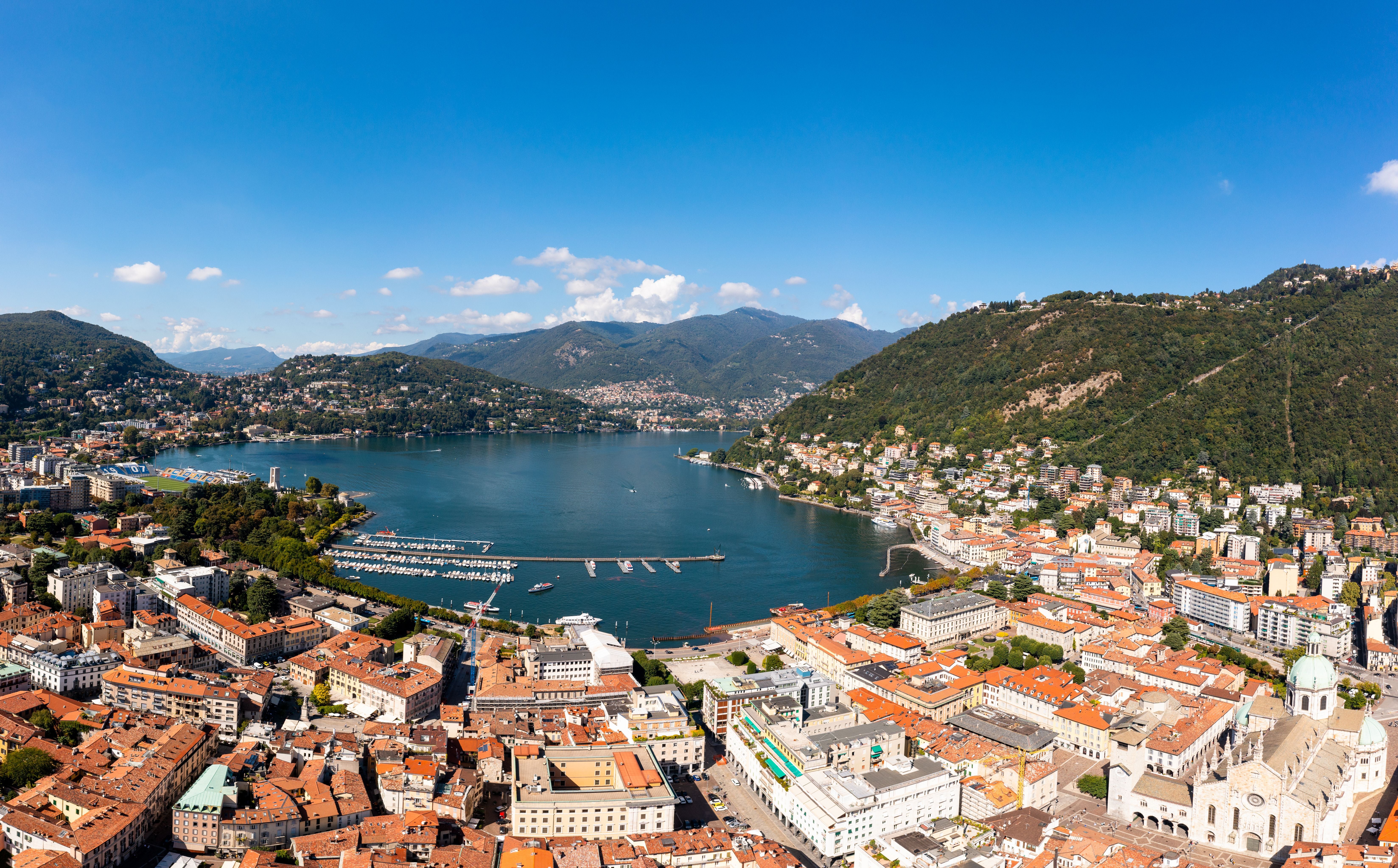 Luftaufnahme von Como am Comer See mit Altstadt, Bergen und blauem Himmel im Sommer.