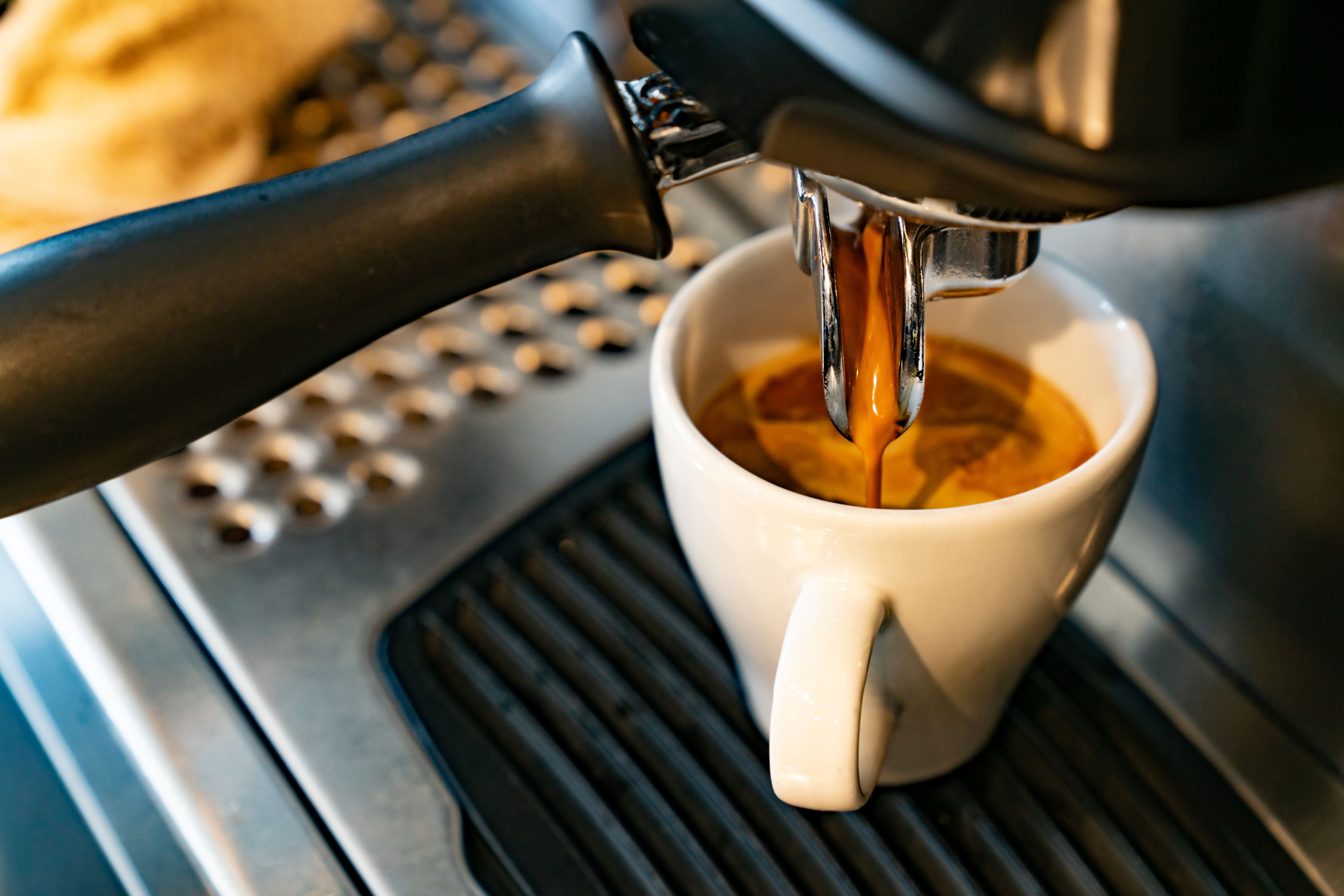 Nahaufnahme einer Espressomaschine, die frischen Espresso in eine weiße Tasse brüht.
