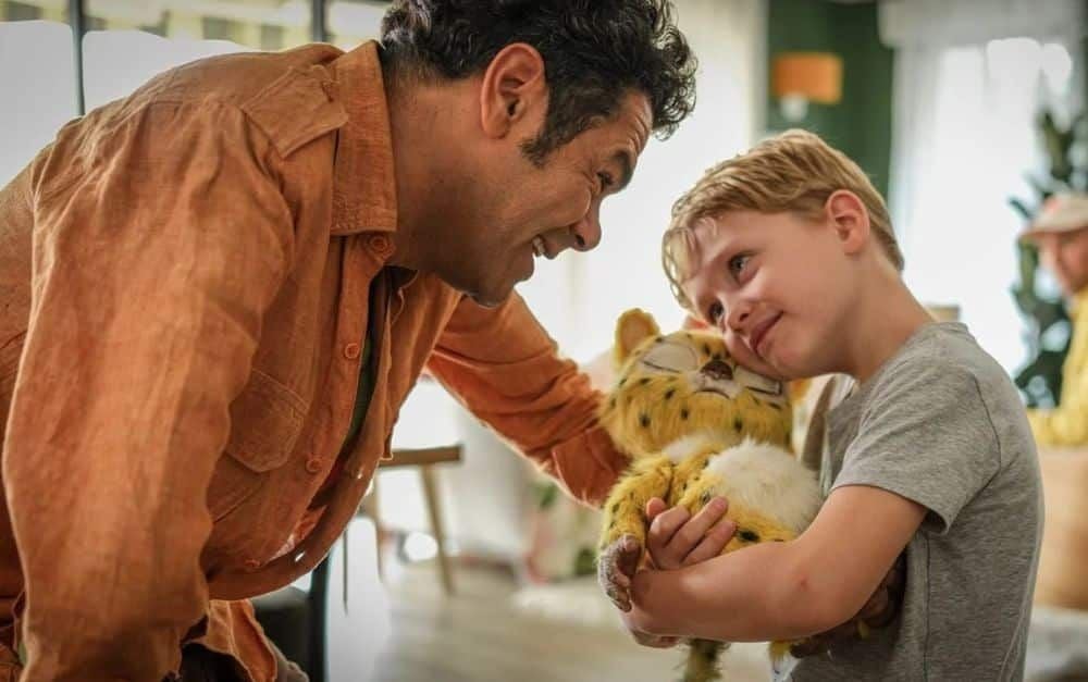 Ein Mann und ein Junge lächeln sich an, der Junge hält ein Marsupilami-Plüschtier im Arm.