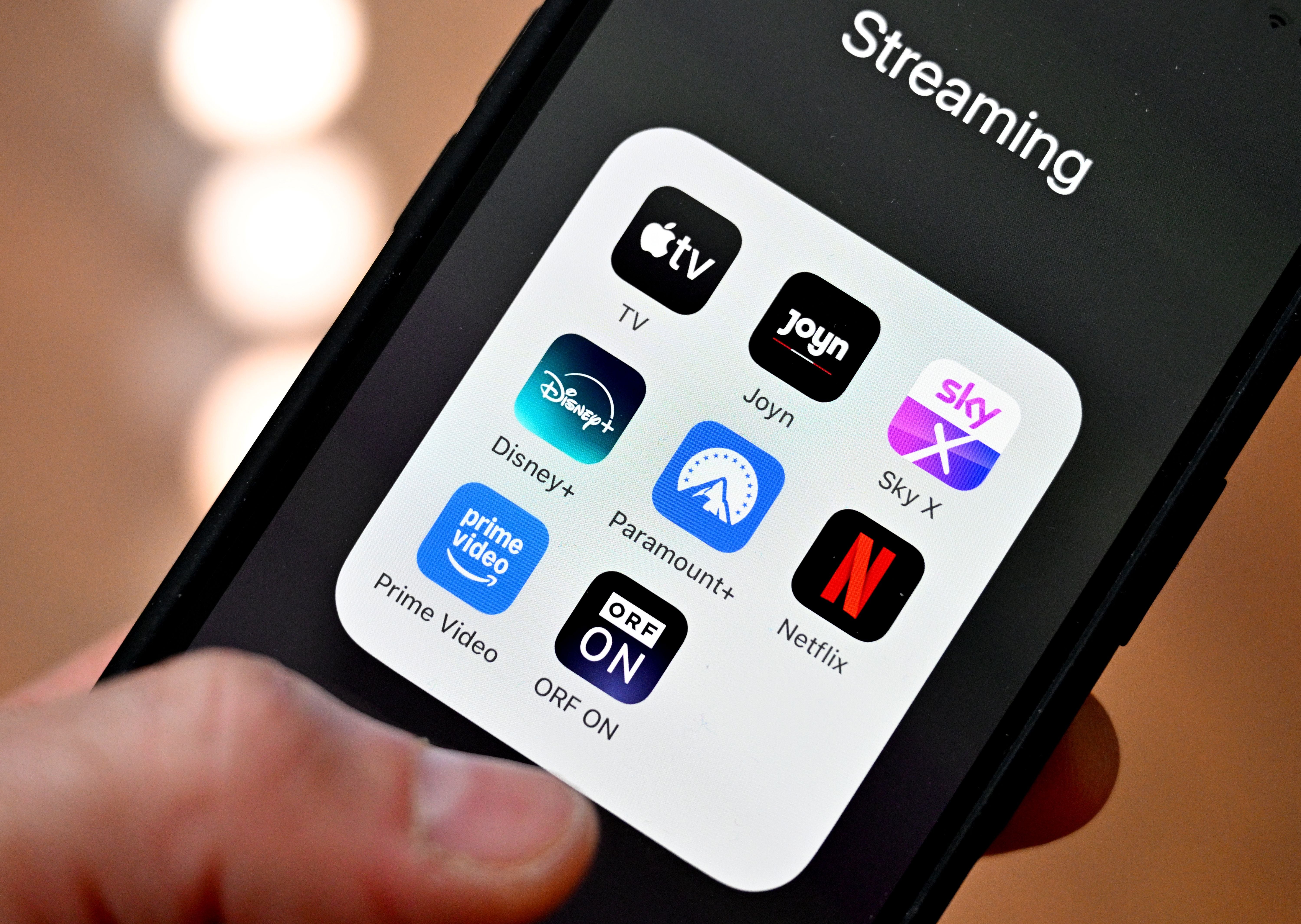 Smartphone mit Streaming-App-Icons wie Netflix, Disney+, Prime Video und Sky X auf dem Bildschirm.