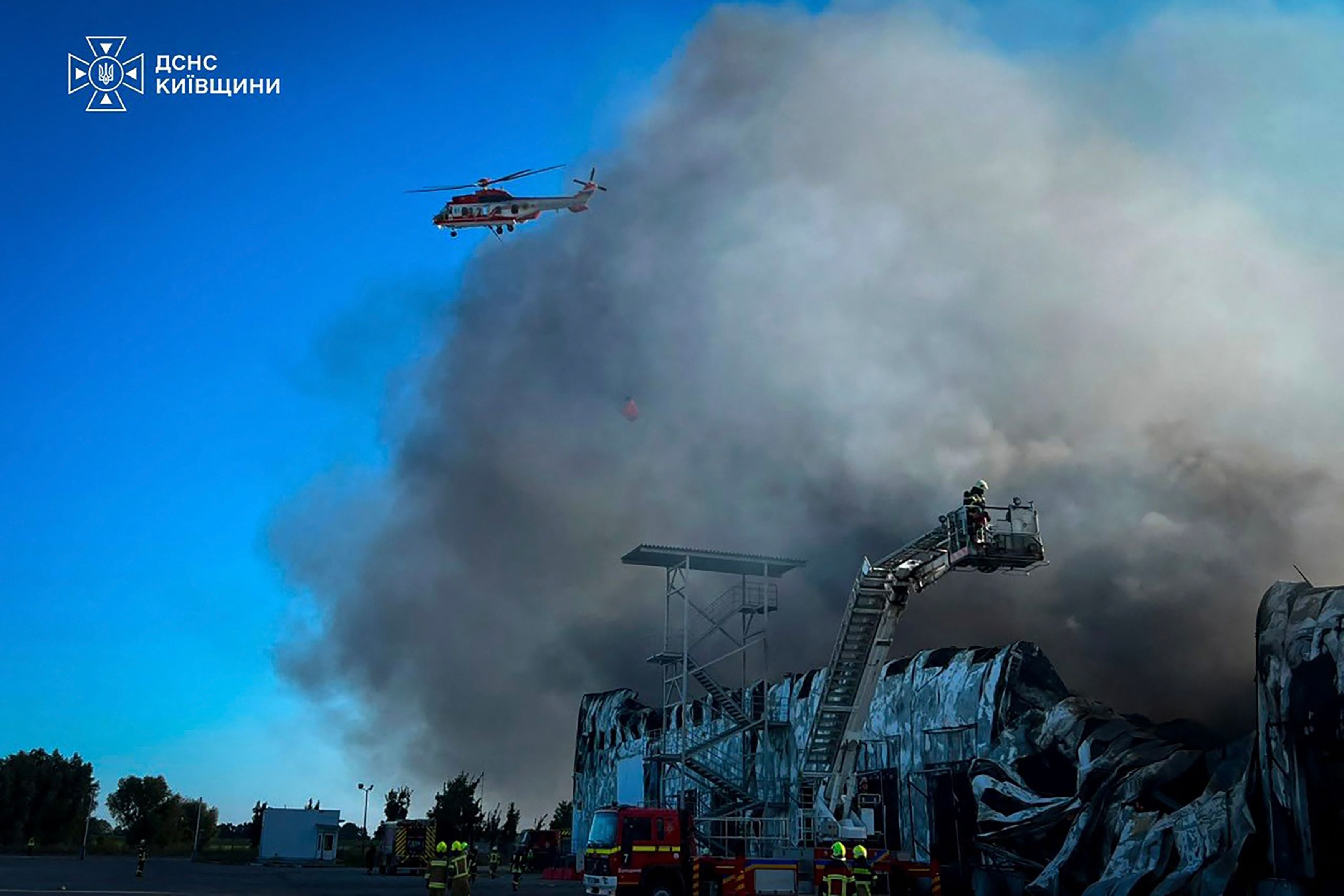 Ukrainische Feuerwehr bekämpft einen Großbrand in einem zerstörten Lagerhaus mit Hubschrauberunterstützung.