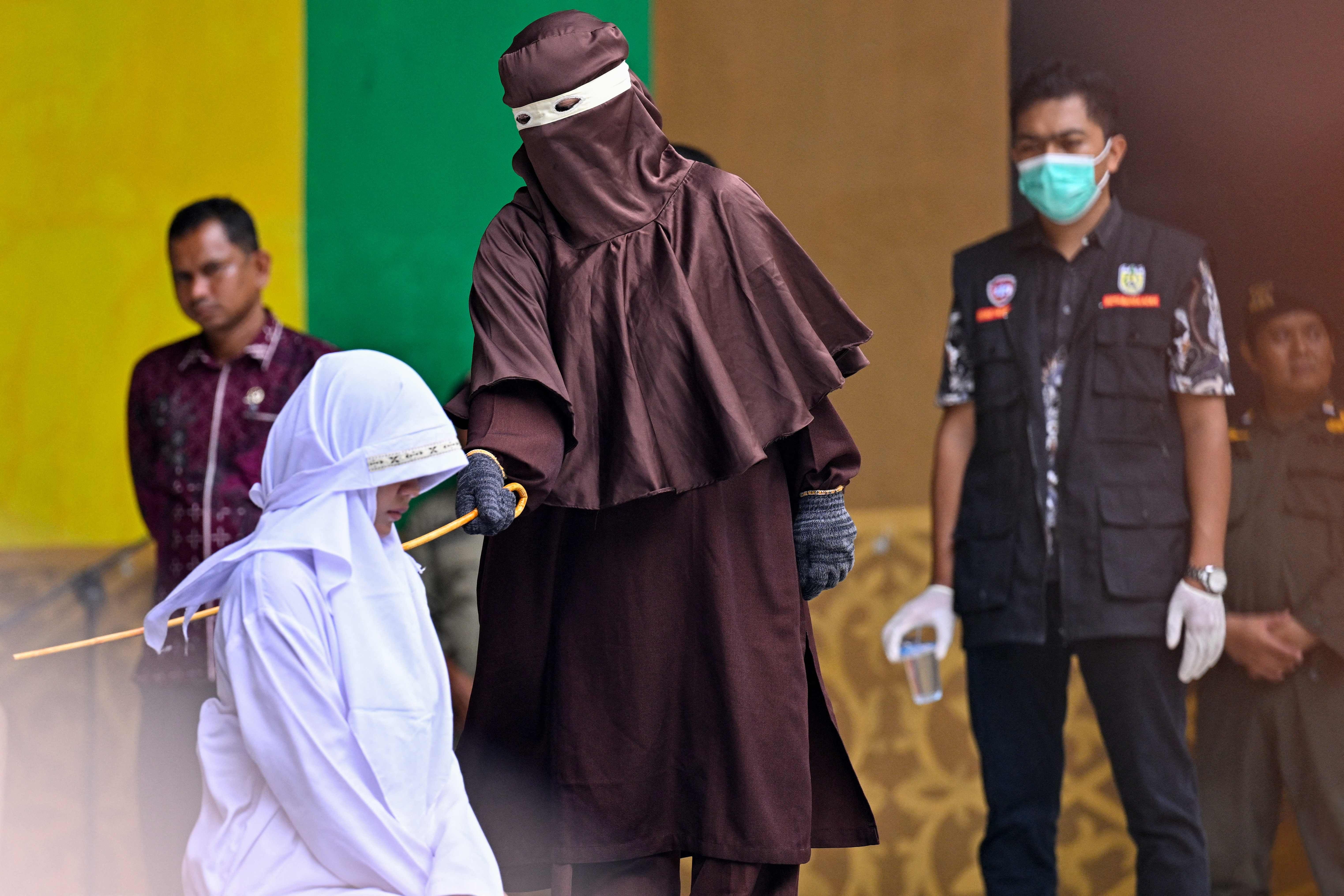 Eine Frau wird in Aceh öffentlich nach islamischem Recht mit einem Stock bestraft.