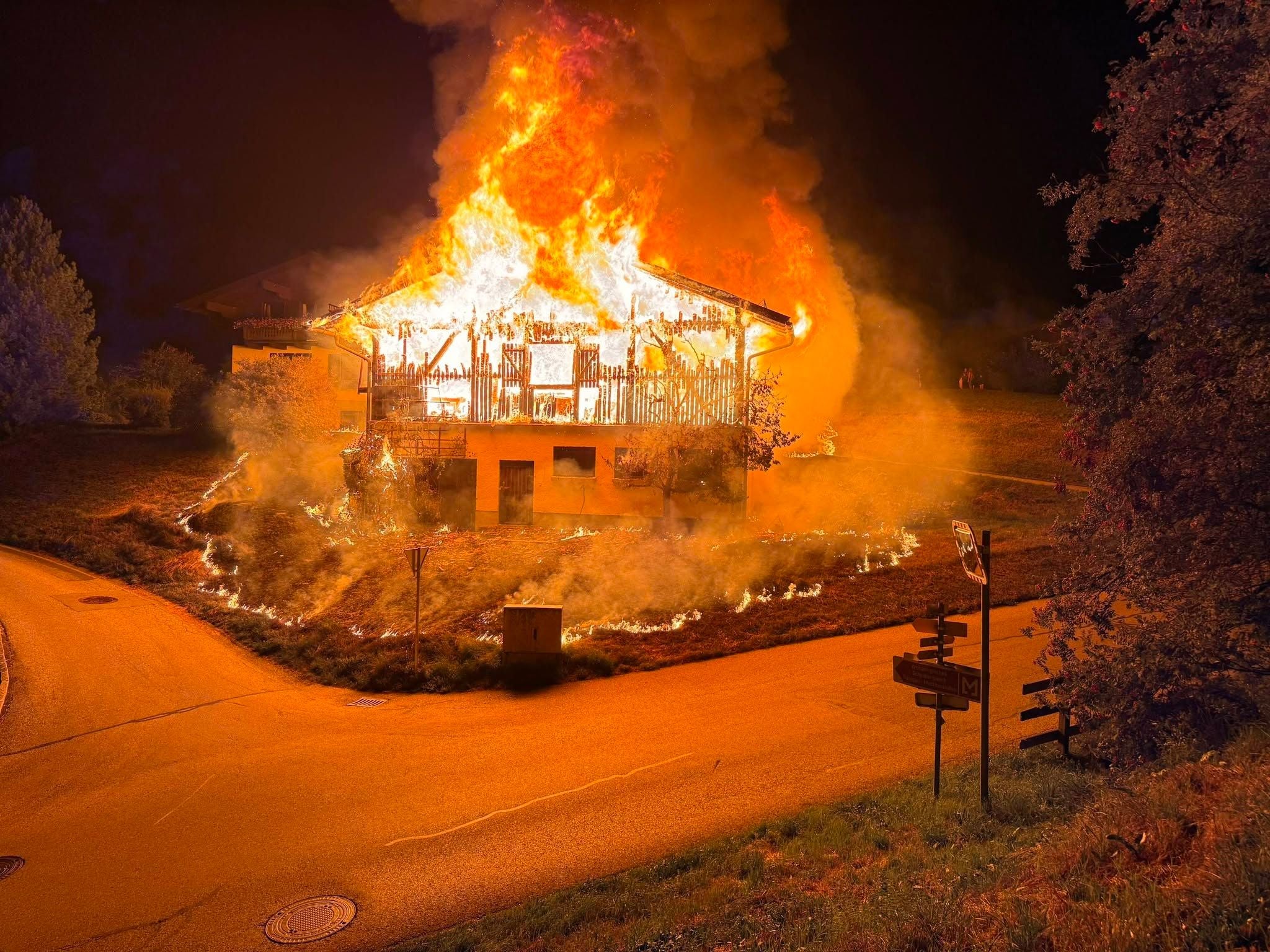 Ein Haus in St. Veit im Pongau steht nachts in Flammen, umgeben von Rauch und Feuer.