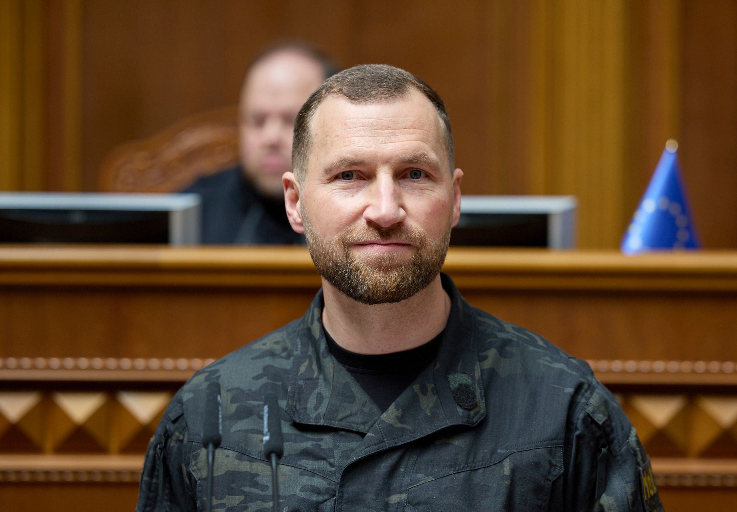 Ein Mann in Militäruniform spricht im ukrainischen Parlament, im Hintergrund eine EU-Flagge.