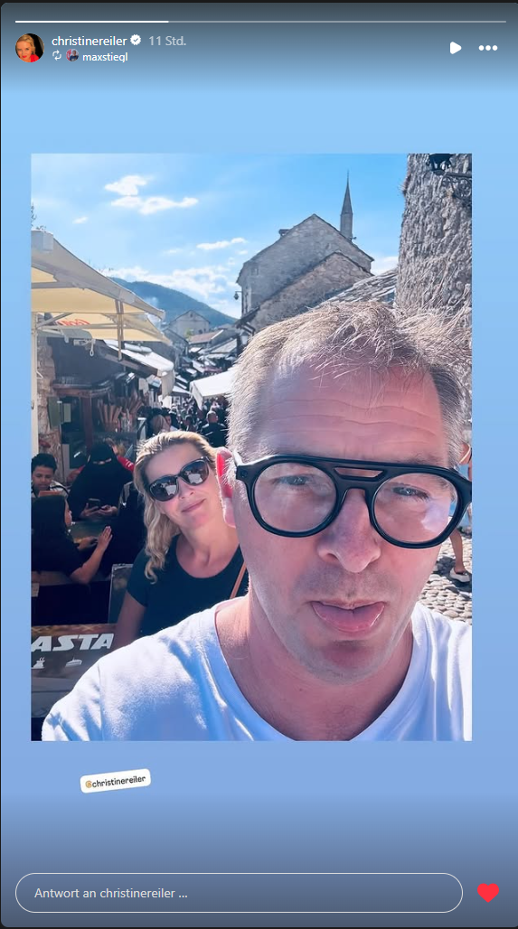 Ein Mann und eine Frau machen ein Selfie in einer belebten Altstadtgasse bei Sonnenschein.