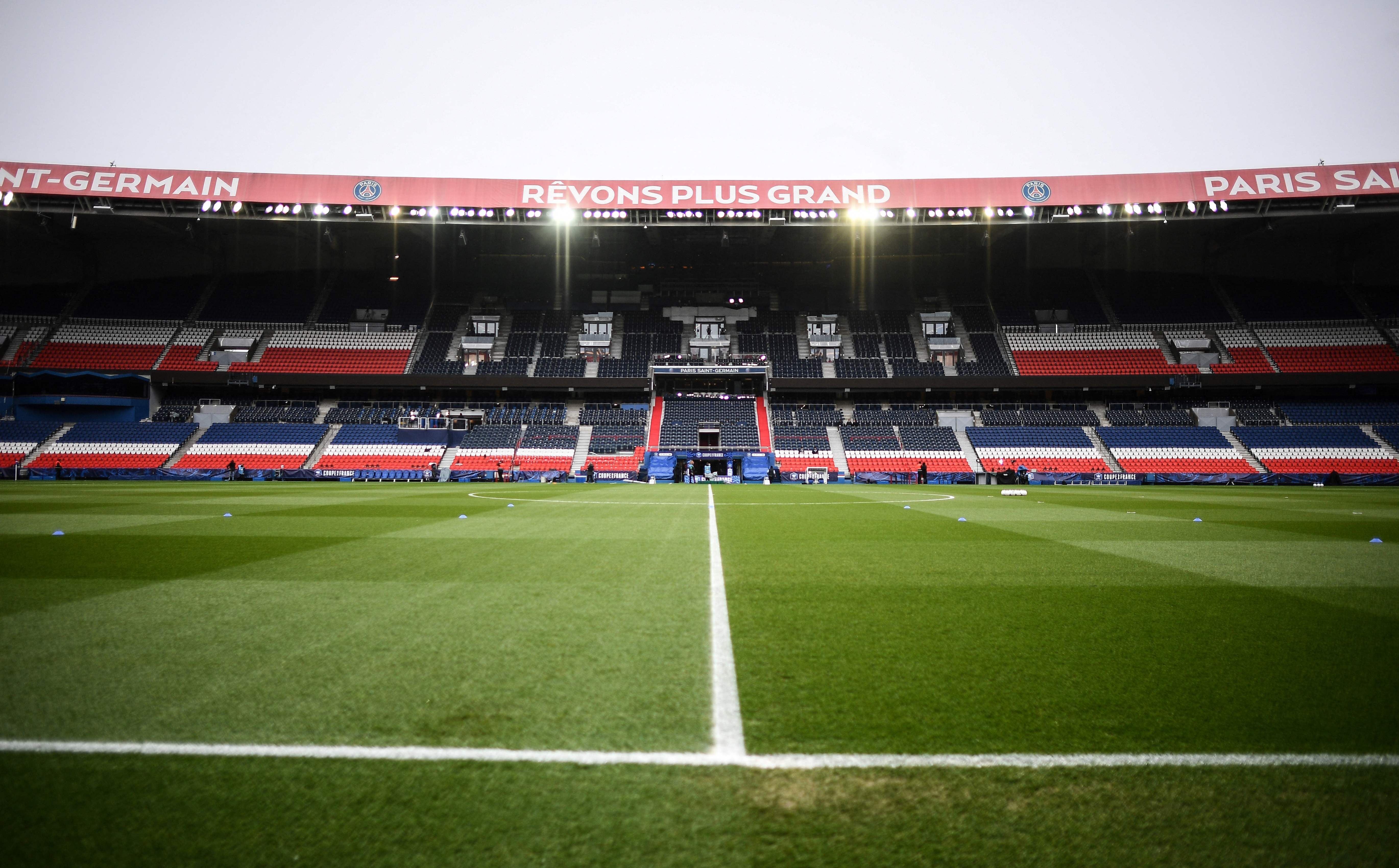 Leeres Fußballstadion Parc des Princes mit grünem Spielfeld und rot-blau-weißen Tribünen.