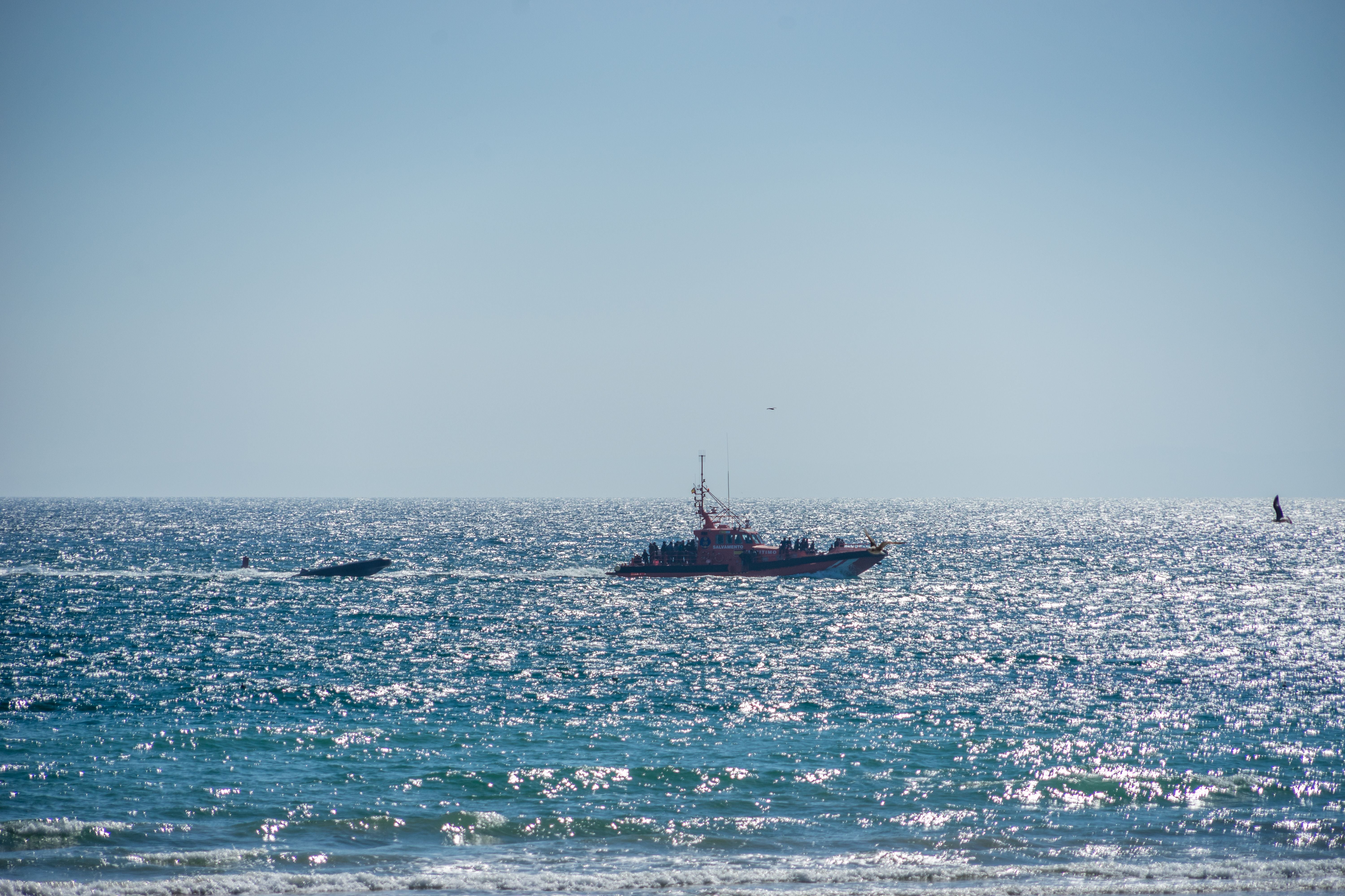 Ein Boot bringt Geflüchtete und ein Schlauchboot auf dem Meer bei Barbate, Spanien, an Land.