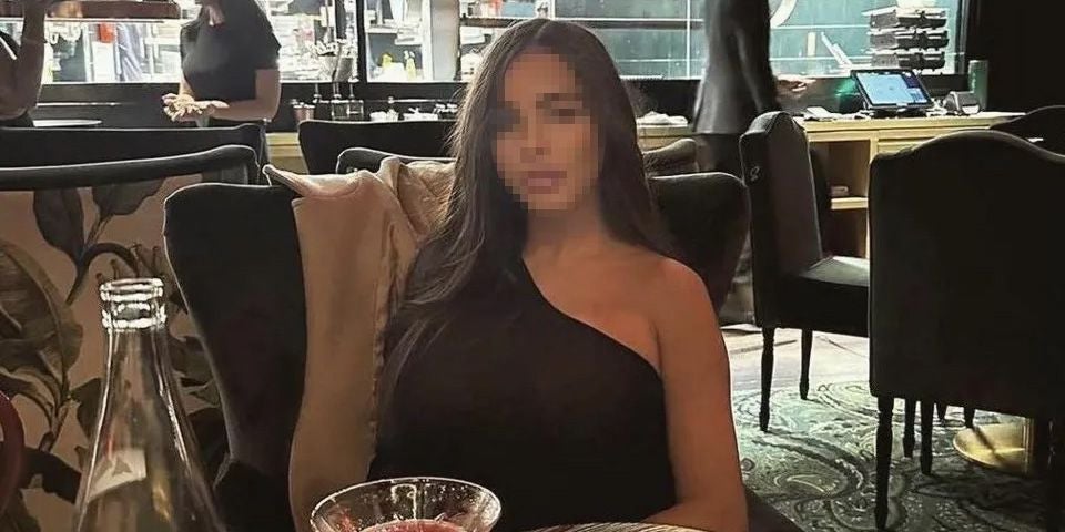 Frau mit langem Haar sitzt in einem Restaurant, Gesicht verpixelt.
