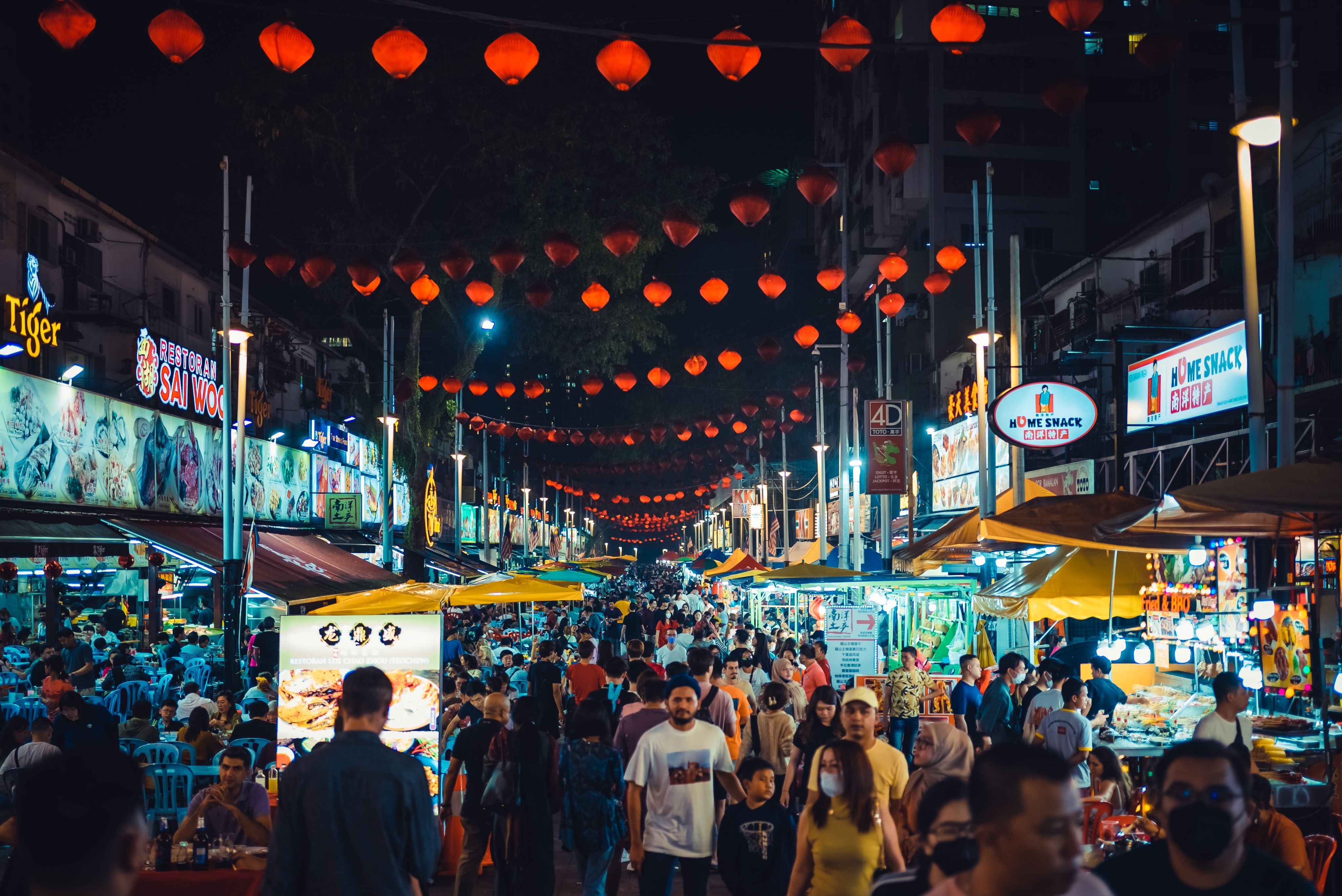 Menschenmenge auf der Jalan-Alor-Food-Street in Kuala Lumpur bei Nacht mit roten Laternen.