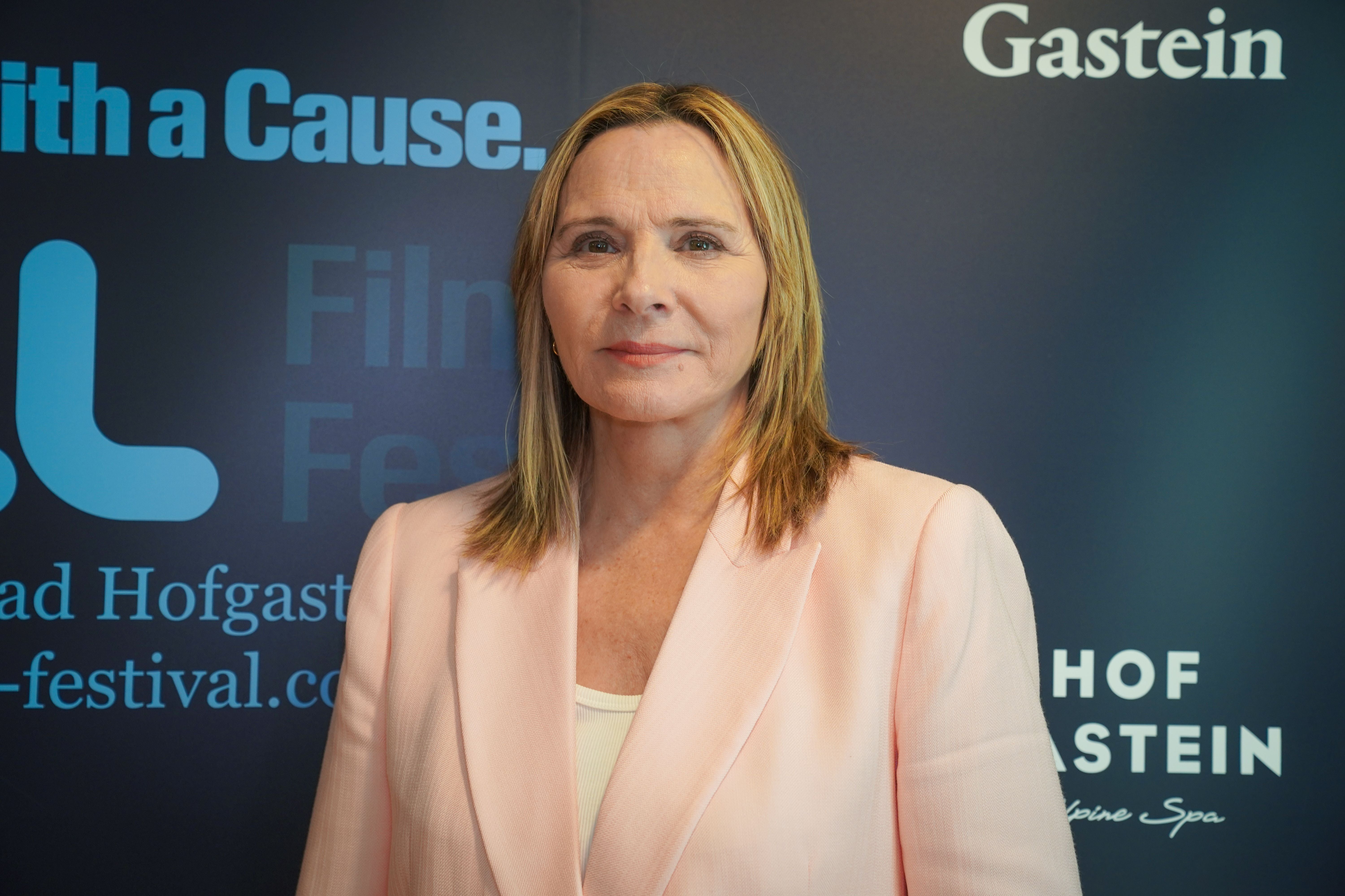 Frau in rosa Blazer steht vor einem Hintergrund mit Festival-Logos.
