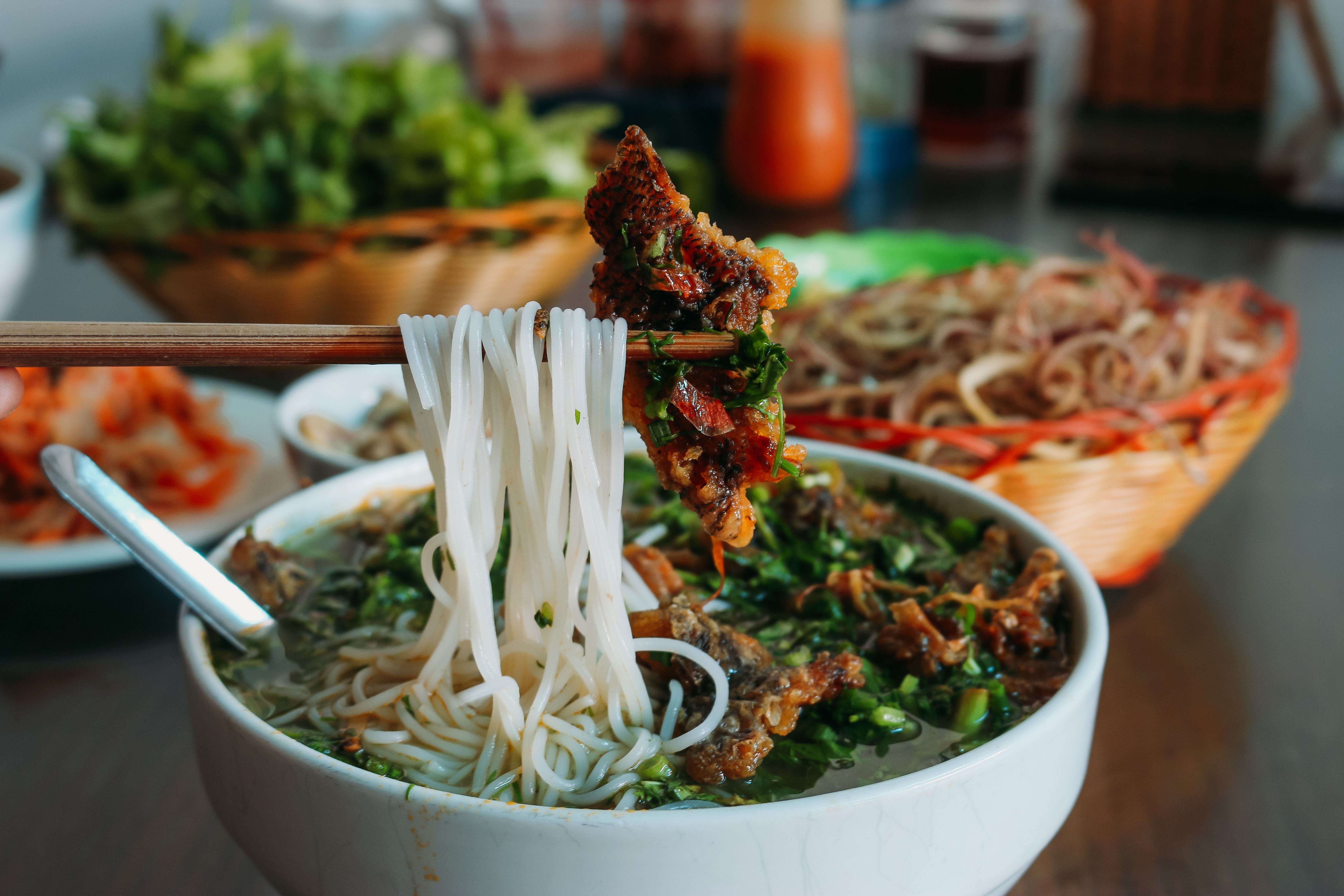 Vietnamesische Reisnudelsuppe mit Brühe, frittiertem Fisch und vielen Frühlingszwiebeln.