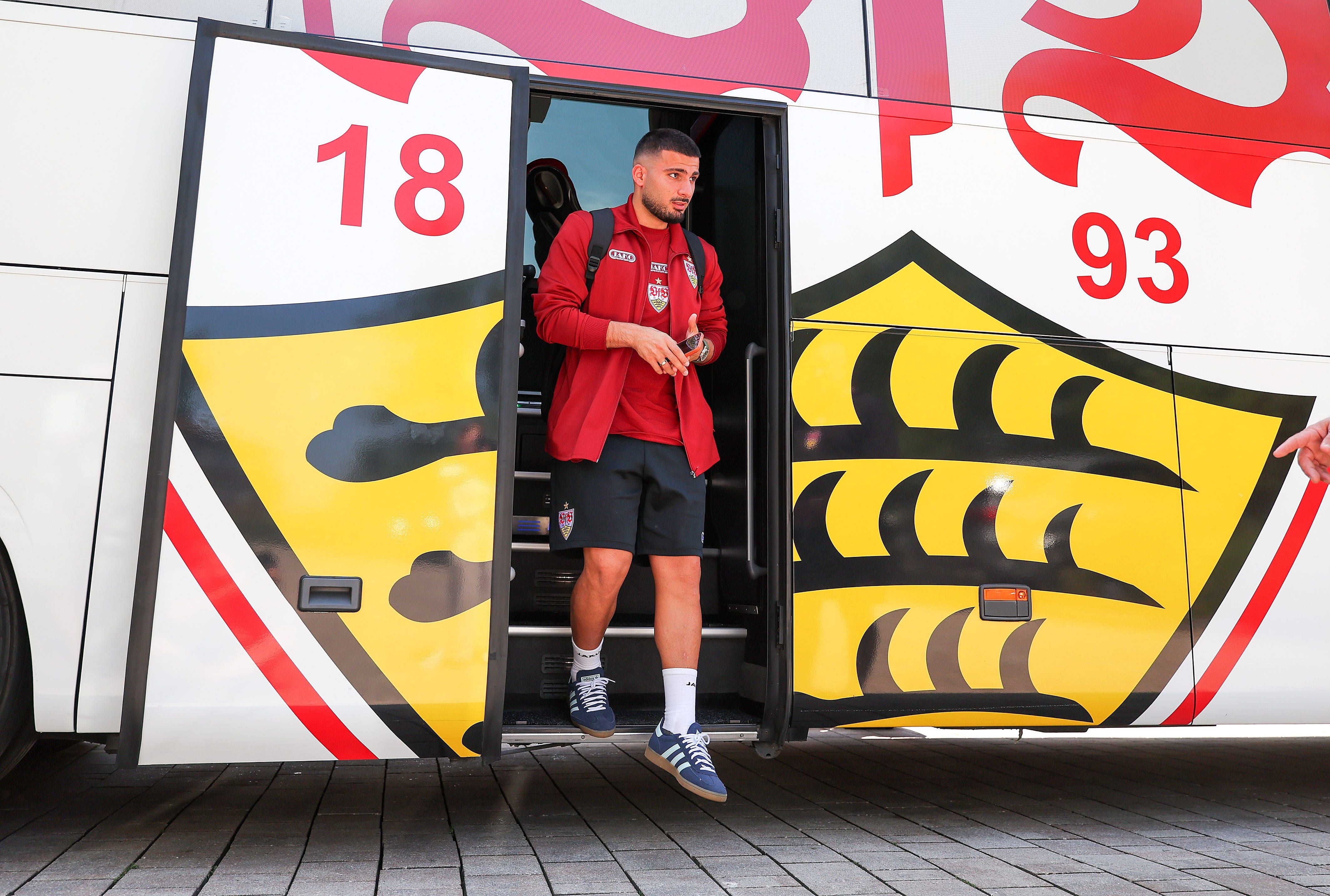 Ein Fußballspieler im VfB Stuttgart-Outfit steigt aus dem Mannschaftsbus aus.
