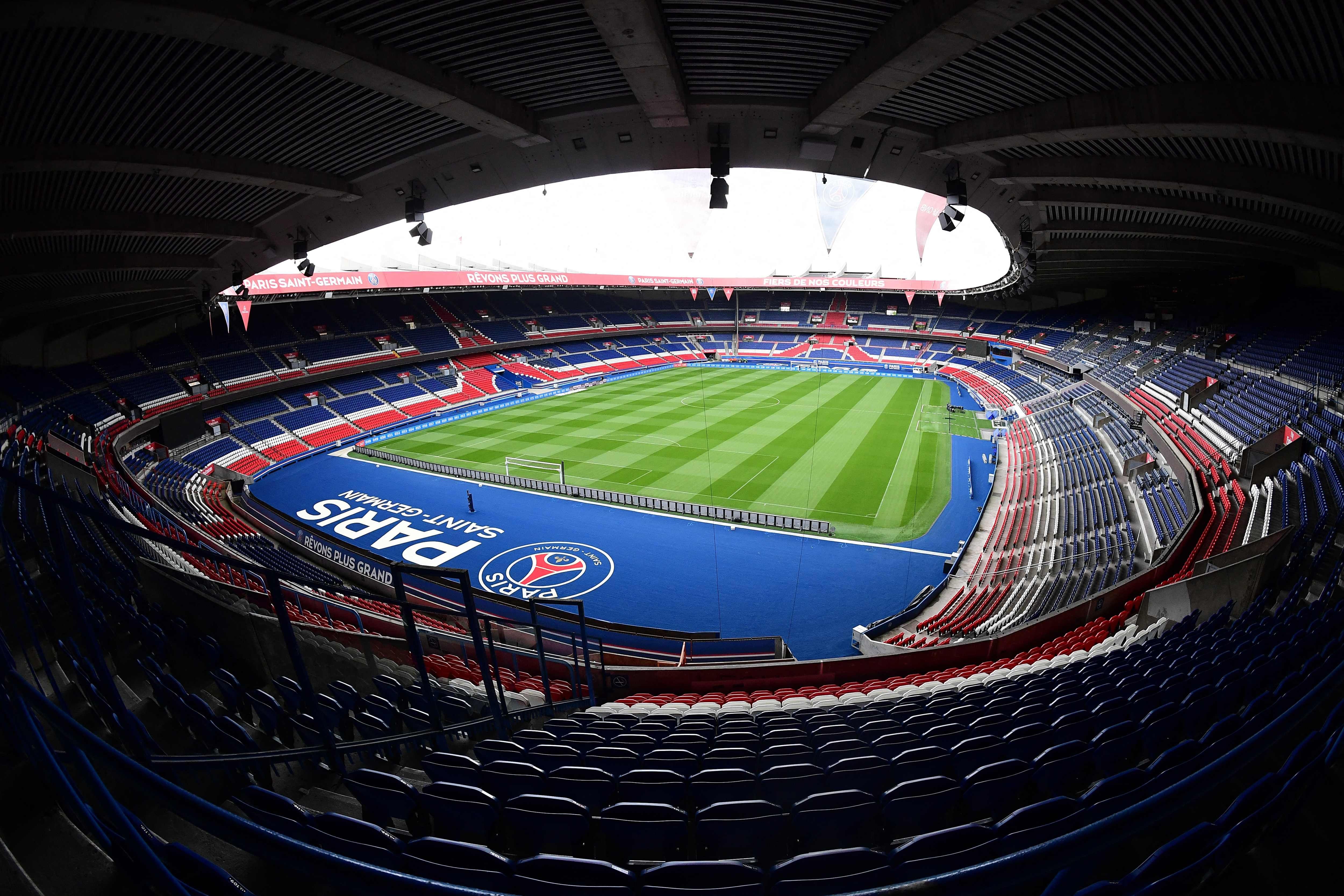 Blick ins leere Parc des Princes Stadion mit grünem Spielfeld und bunten Tribünen in Paris.