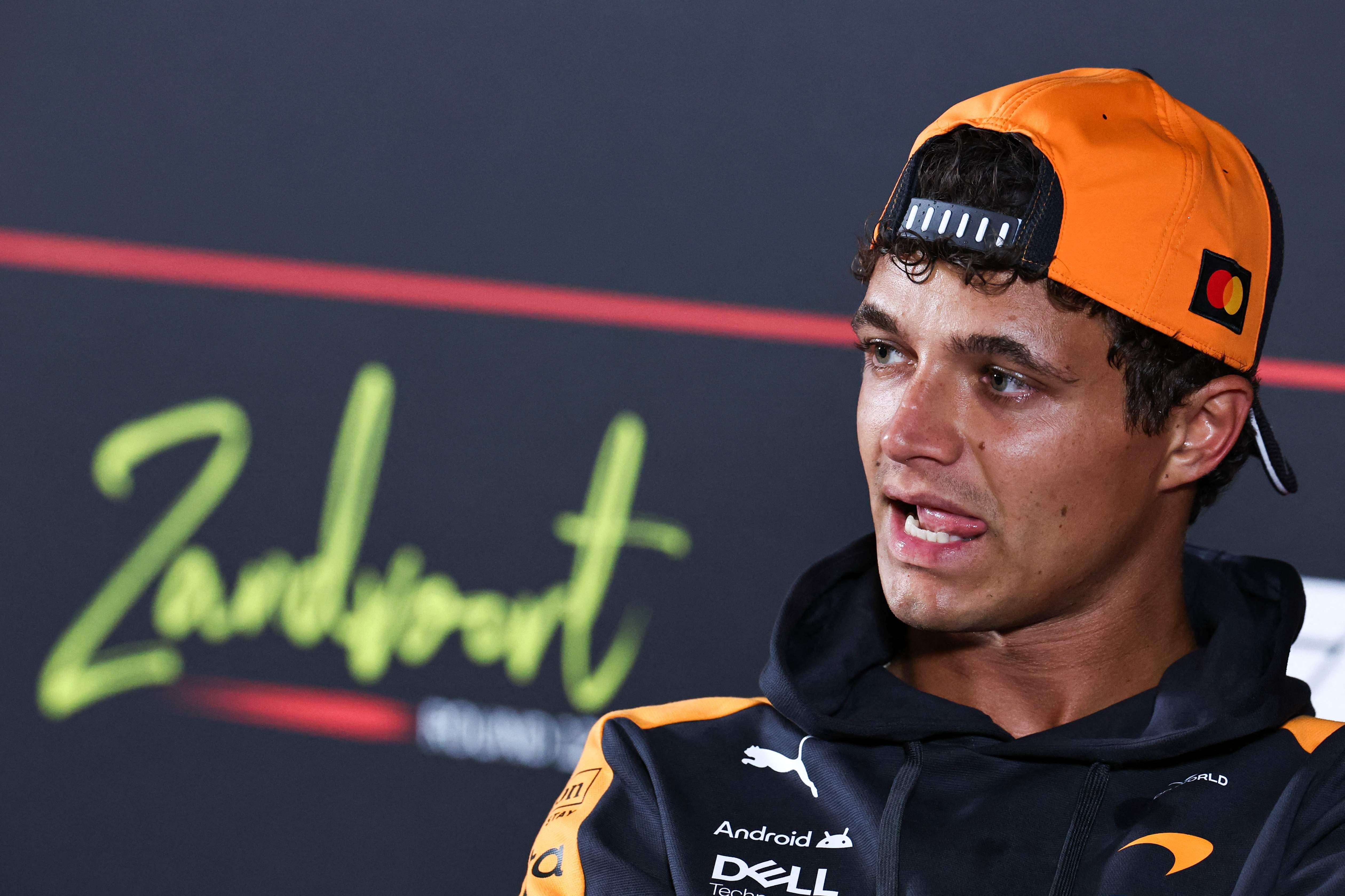 Lando Norris mit orangefarbener Kappe bei einer Pressekonferenz in Zandvoort.