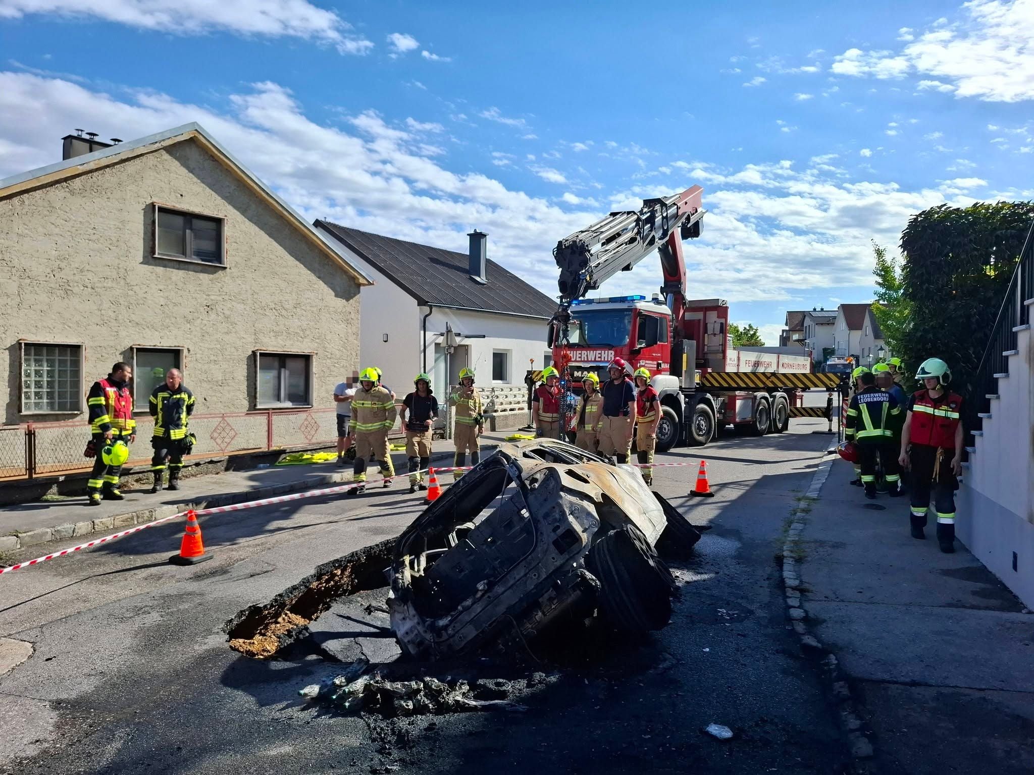 Feuerwehrleute bargen das komplett ausgebrannte, von der Straße verschlugene Auto.